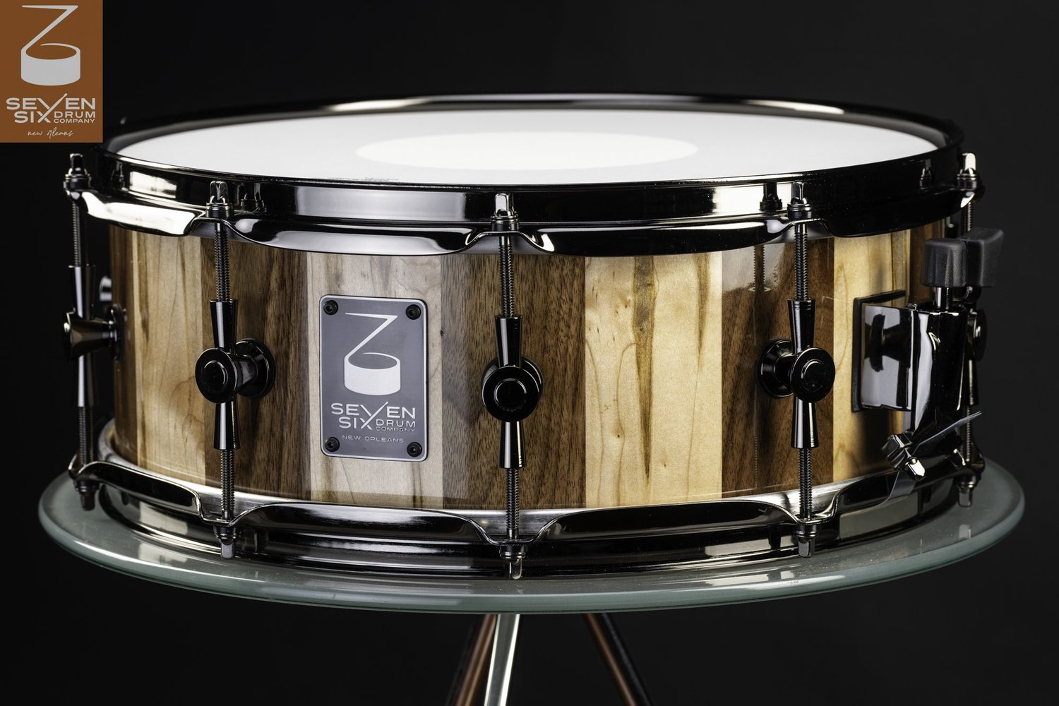 Handmade stave snare drum with a high-gloss striped wood shell, black nickel hoops, and single-point lugs.