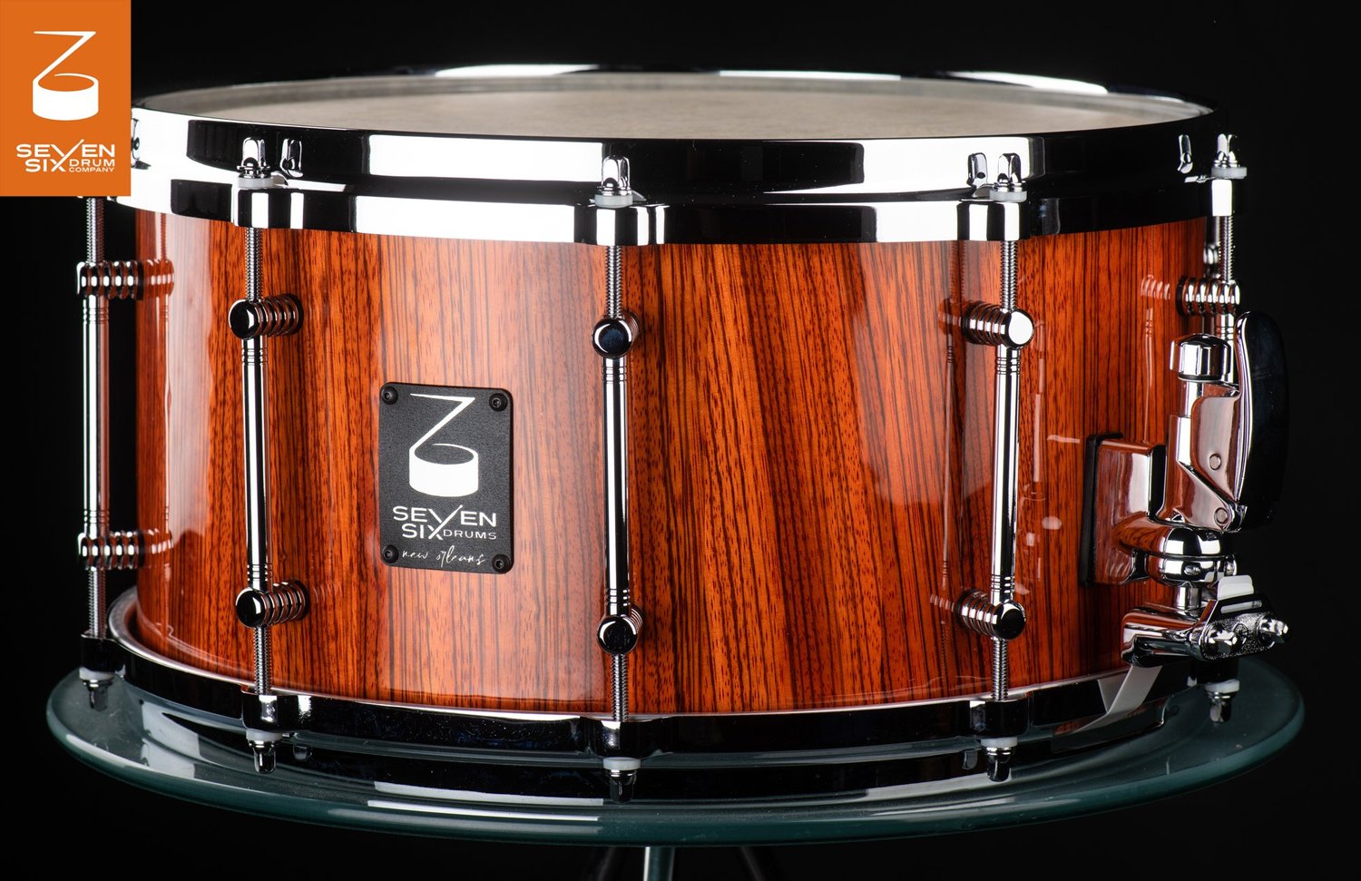 Snare drum featuring a glossy vertical-grain wood shell, polished chrome hoops, and tube lugs.
