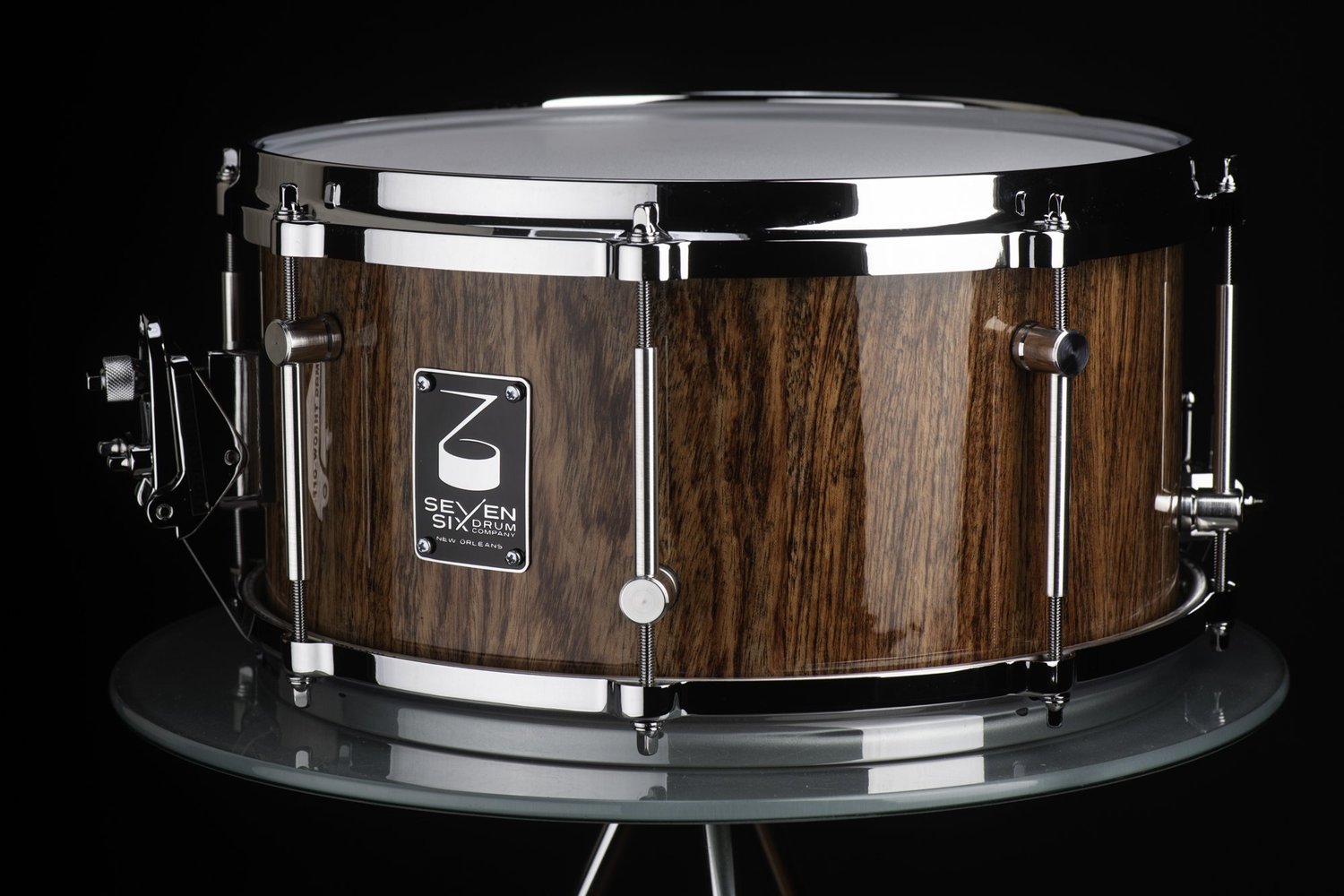 Handmade snare drum with a glossy natural wood finish, polished chrome hoops, and sleek tube lugs.