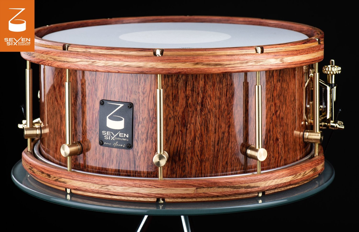 Handmade snare drum with a high-gloss natural wood shell, matching wooden hoops, and brushed brass hardware.