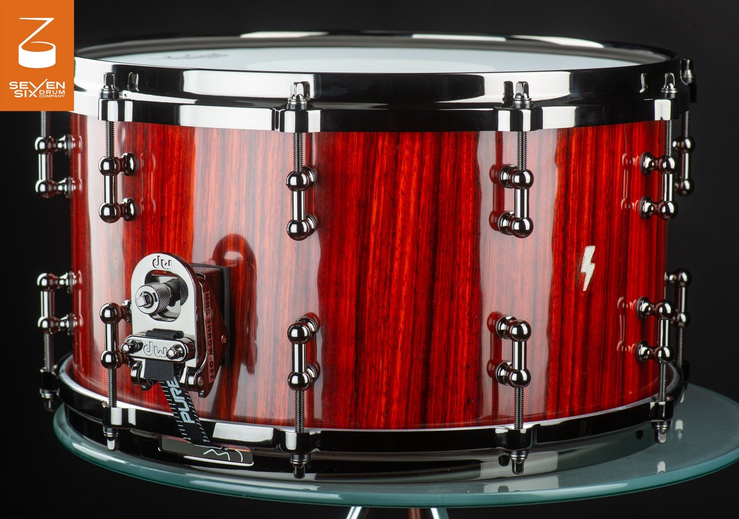 Handmade snare drum featuring a glossy reddish vertical-grain wood shell, chrome tube lugs, and a DW MAG throw-off.