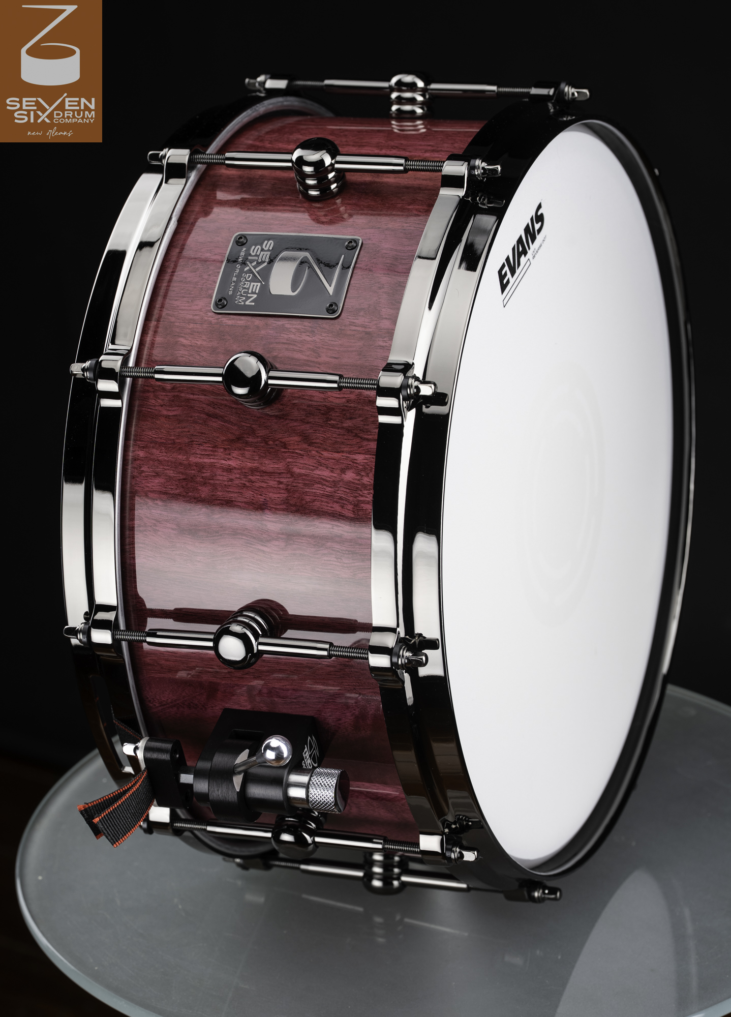Handmade snare drum with a glossy purple wood finish, polished black nickel hoops, center lugs, and a snare throw-off.