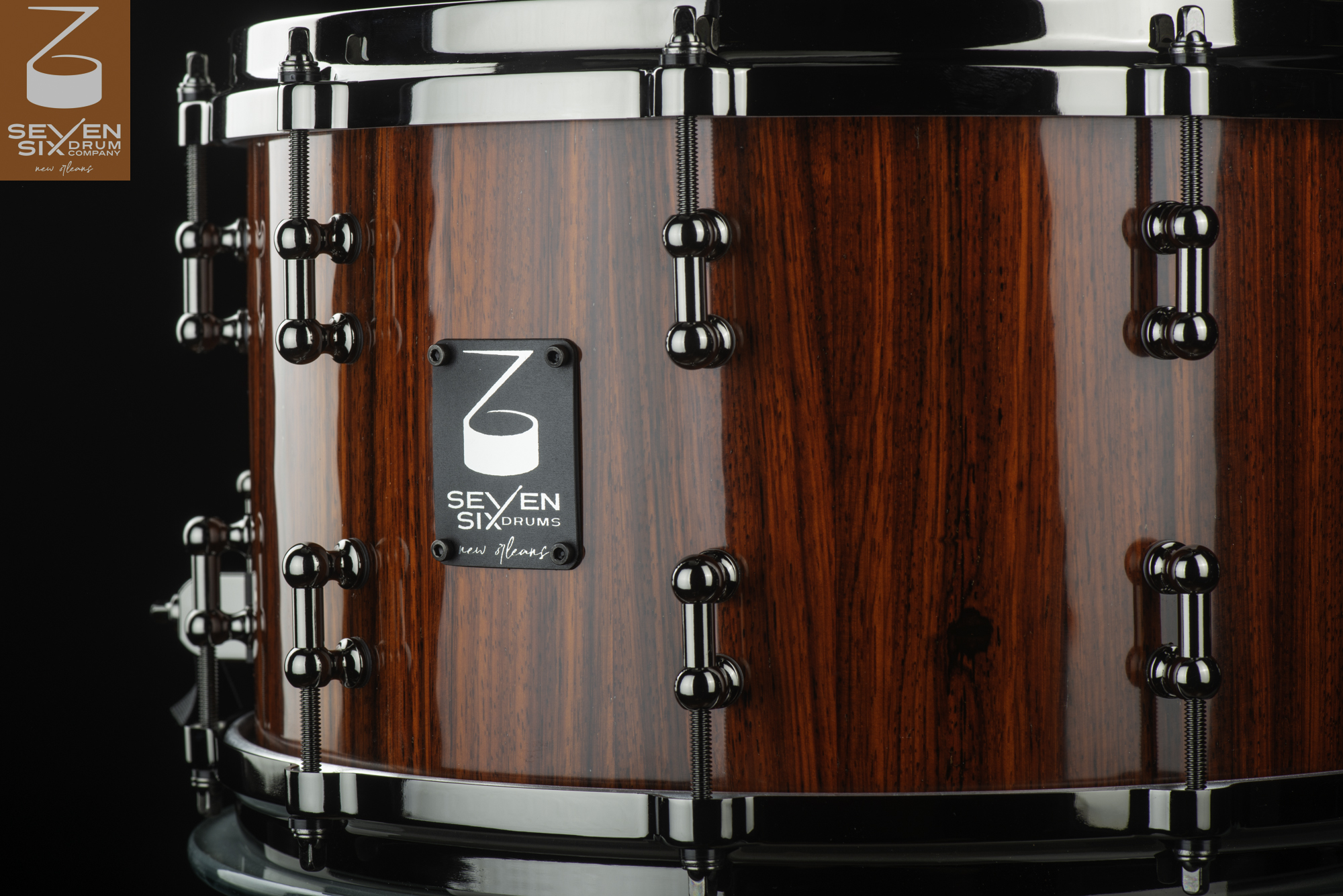 Handmade snare drum featuring a glossy red wood grain shell, black nickel lugs, and matching hoops.