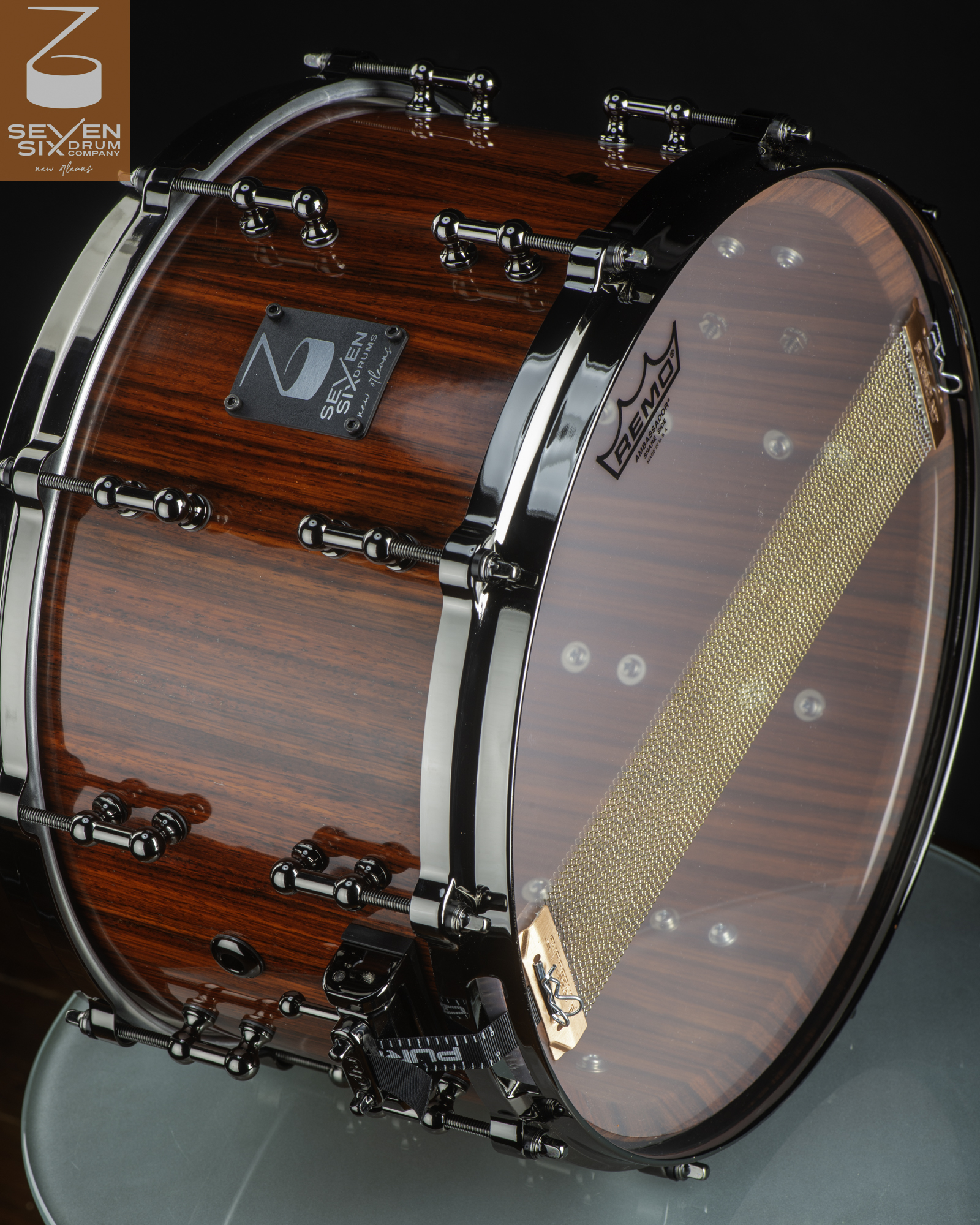 Handmade deep snare drum with a glossy red wood finish, black nickel tube lugs, and brass snare wires.