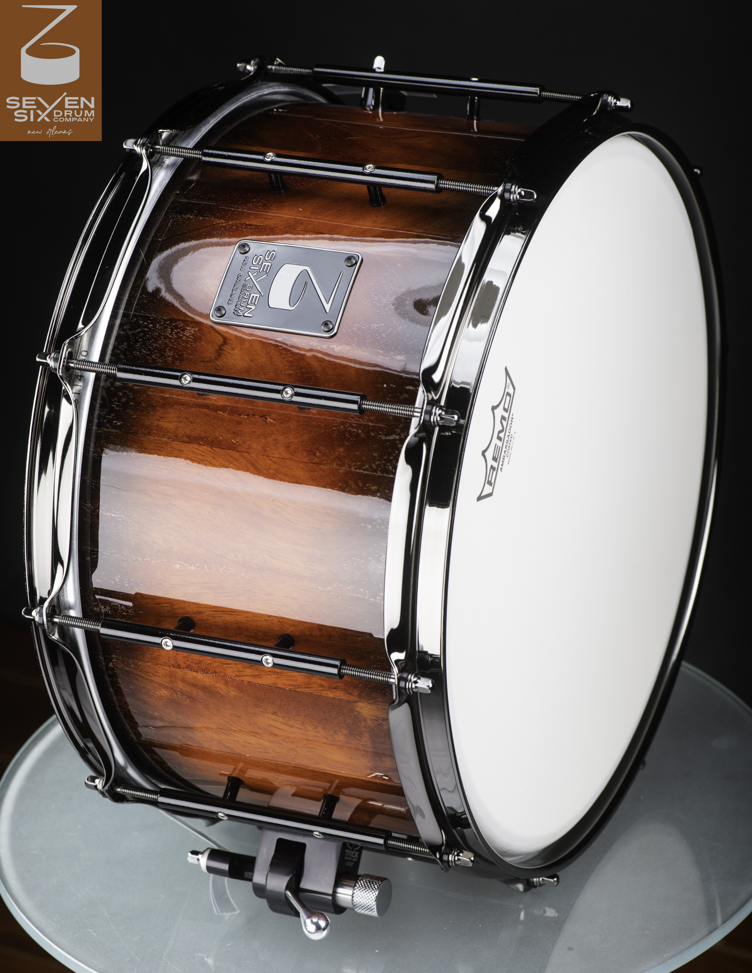 Handmade wood snare drum with a high-gloss reddish-brown finish, black tube lugs, and chrome hoops.