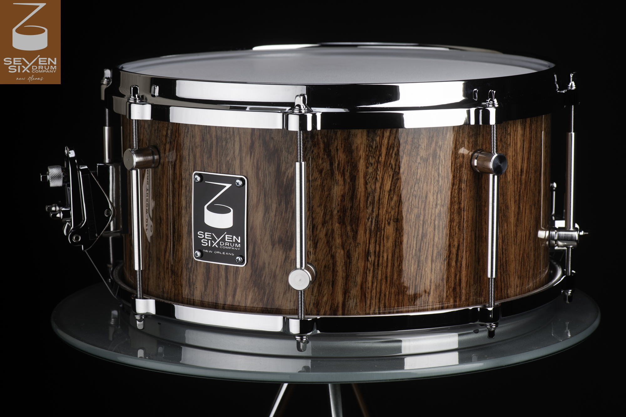 Handmade snare drum featuring a high-gloss wood grain shell, polished chrome hoops, and sleek tube lugs.