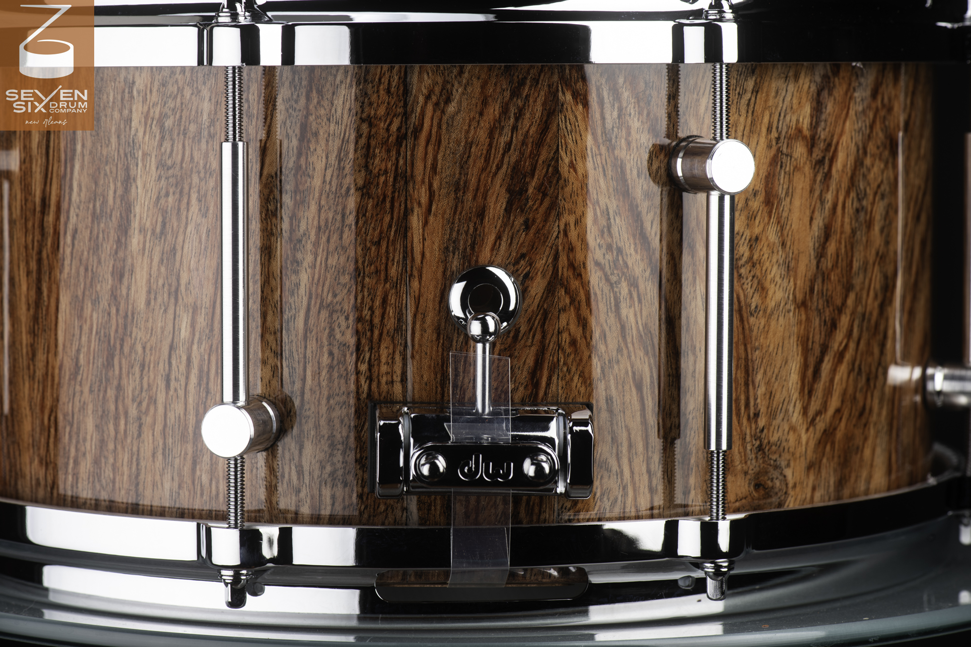 Snare drum with a high-gloss wood grain shell, chrome hoops, tubular lugs, and a DW butt plate.
