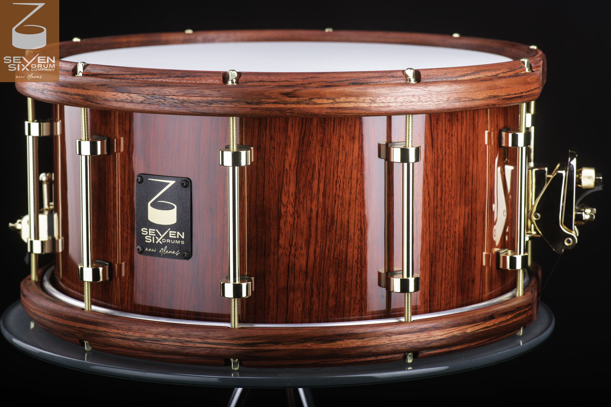 Glossy red wood snare drum featuring matching wooden hoops and polished gold tube lugs.