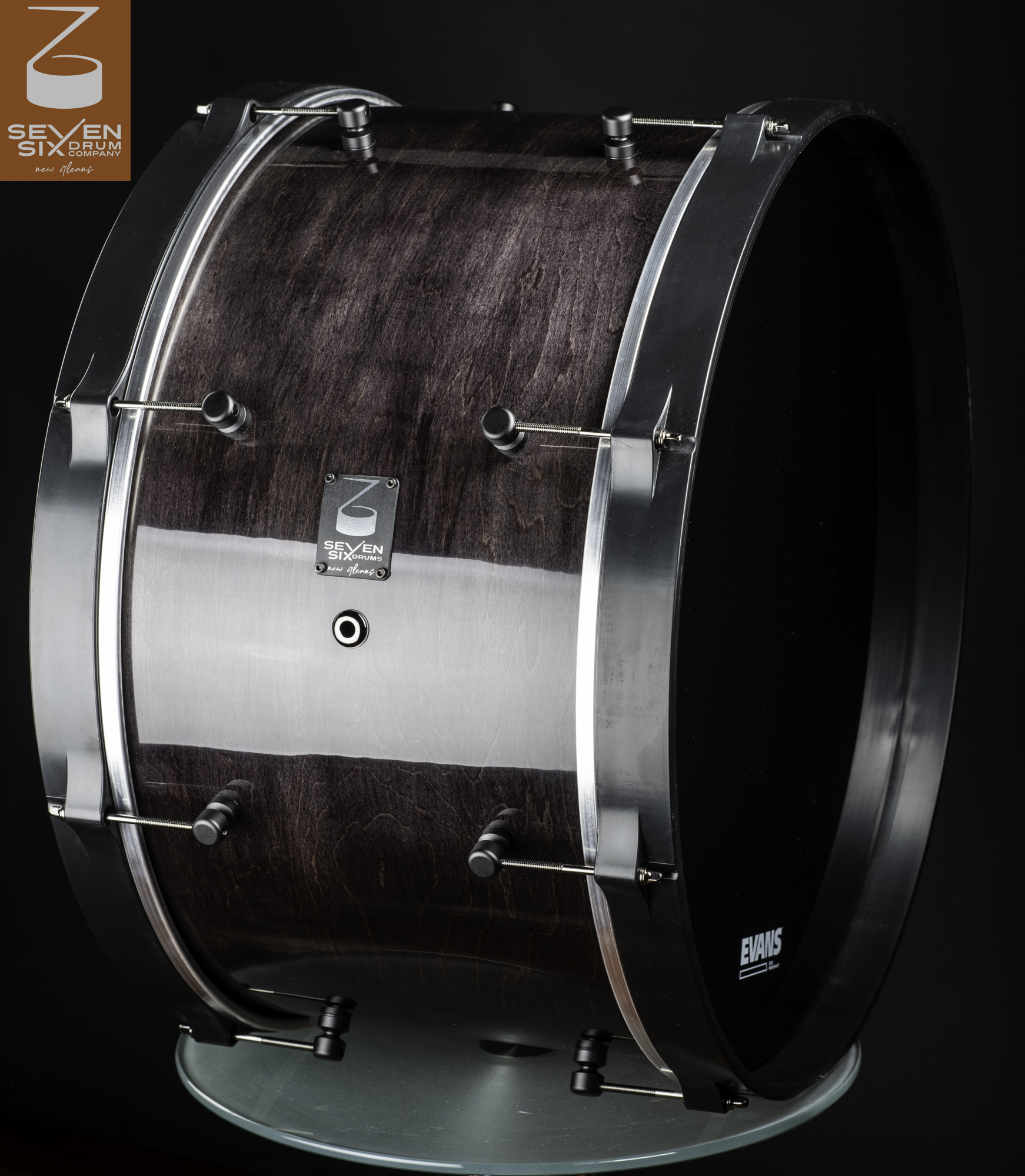 Dark purple-stained wood bass drum with a high-gloss finish, brushed metal hoops, and minimalist black lugs.