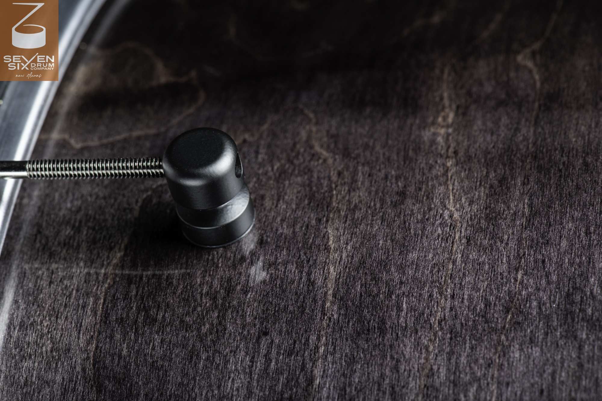Dark stained wood snare drum shell with visible grain, featuring a matte black cylindrical lug and tension rod.