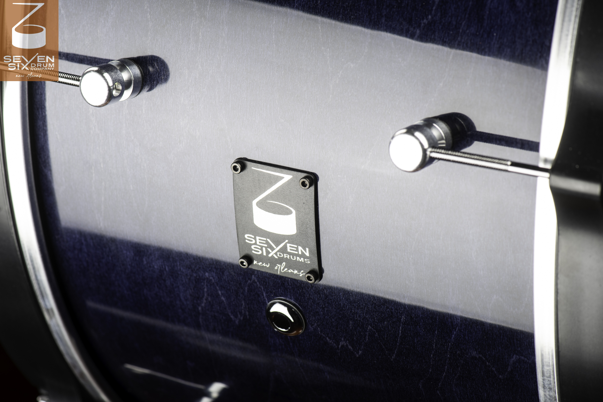 Snare drum shell with a gloss blue burst wood finish, chrome tube lugs, and a black Seven Six Drums badge.