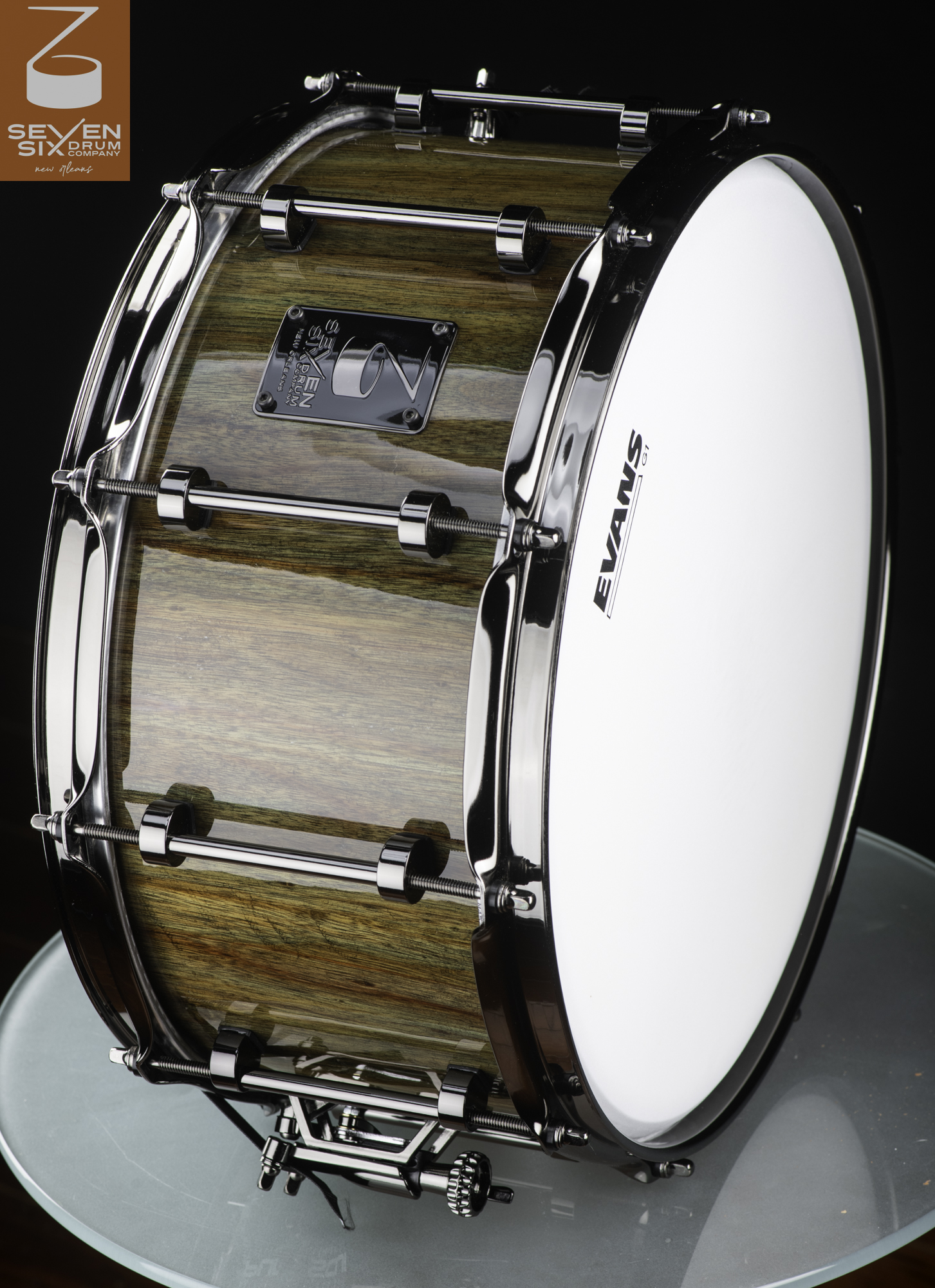 Handmade snare drum with a glossy natural wood grain shell, polished chrome tube lugs, and matching hoops.