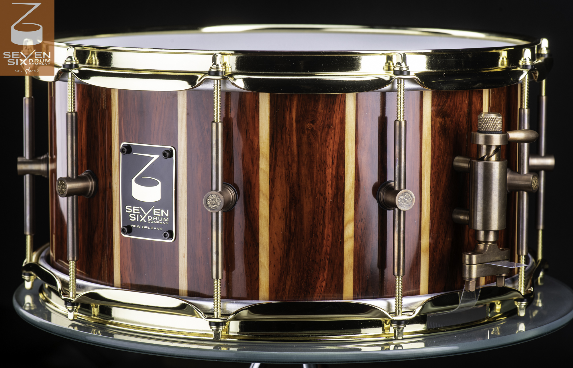 Handmade snare drum featuring a glossy red and blonde striped wood shell, polished brass hoops, and antique bronze hardware.