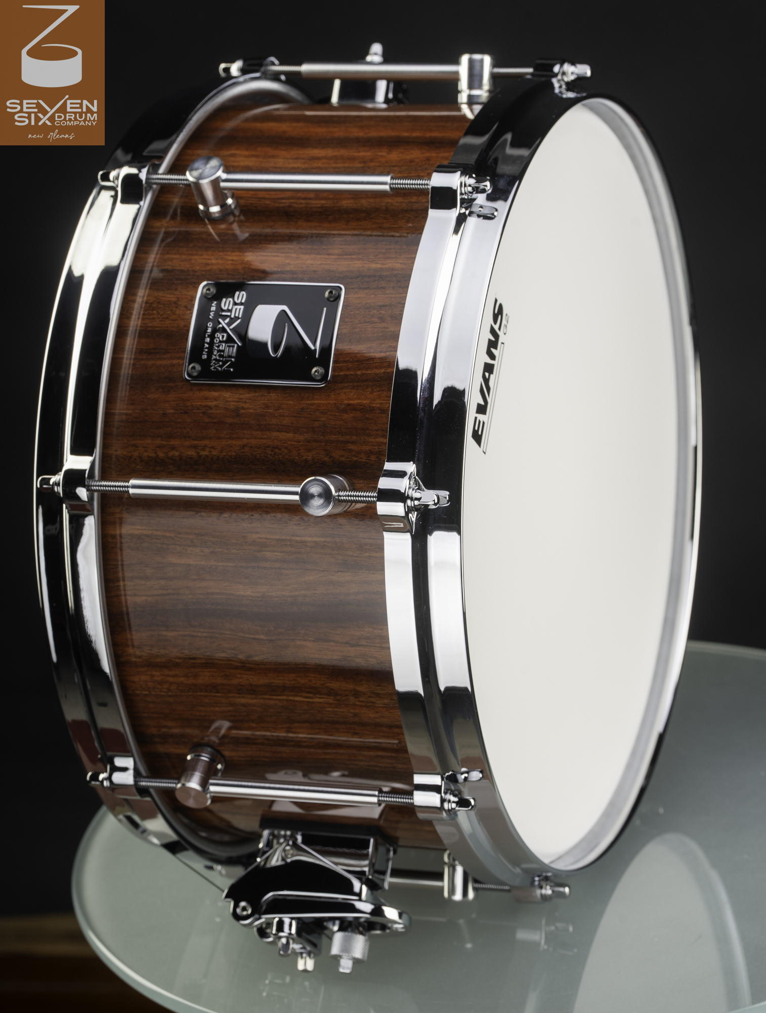 Handmade snare drum with a glossy reddish-brown wood shell, chrome hoops, and tube lugs.
