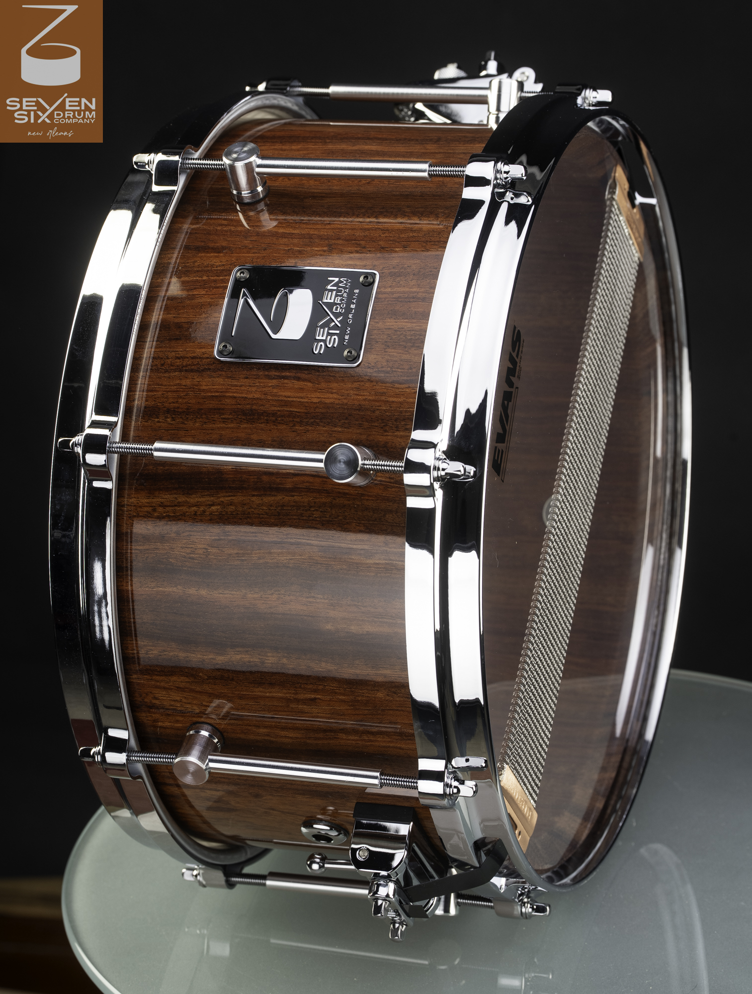 Handmade snare drum with a high-gloss brown wood finish, polished chrome hoops, and tube lugs.