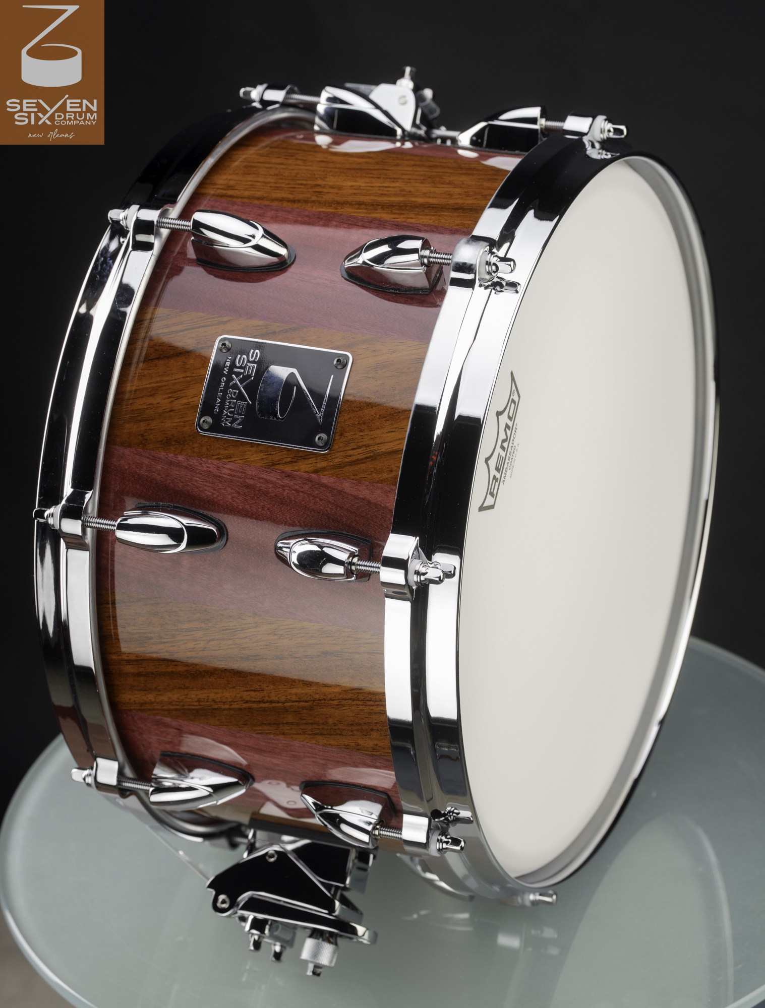 Handmade snare drum with a high-gloss striped wood shell, chrome lugs, and polished hoops.