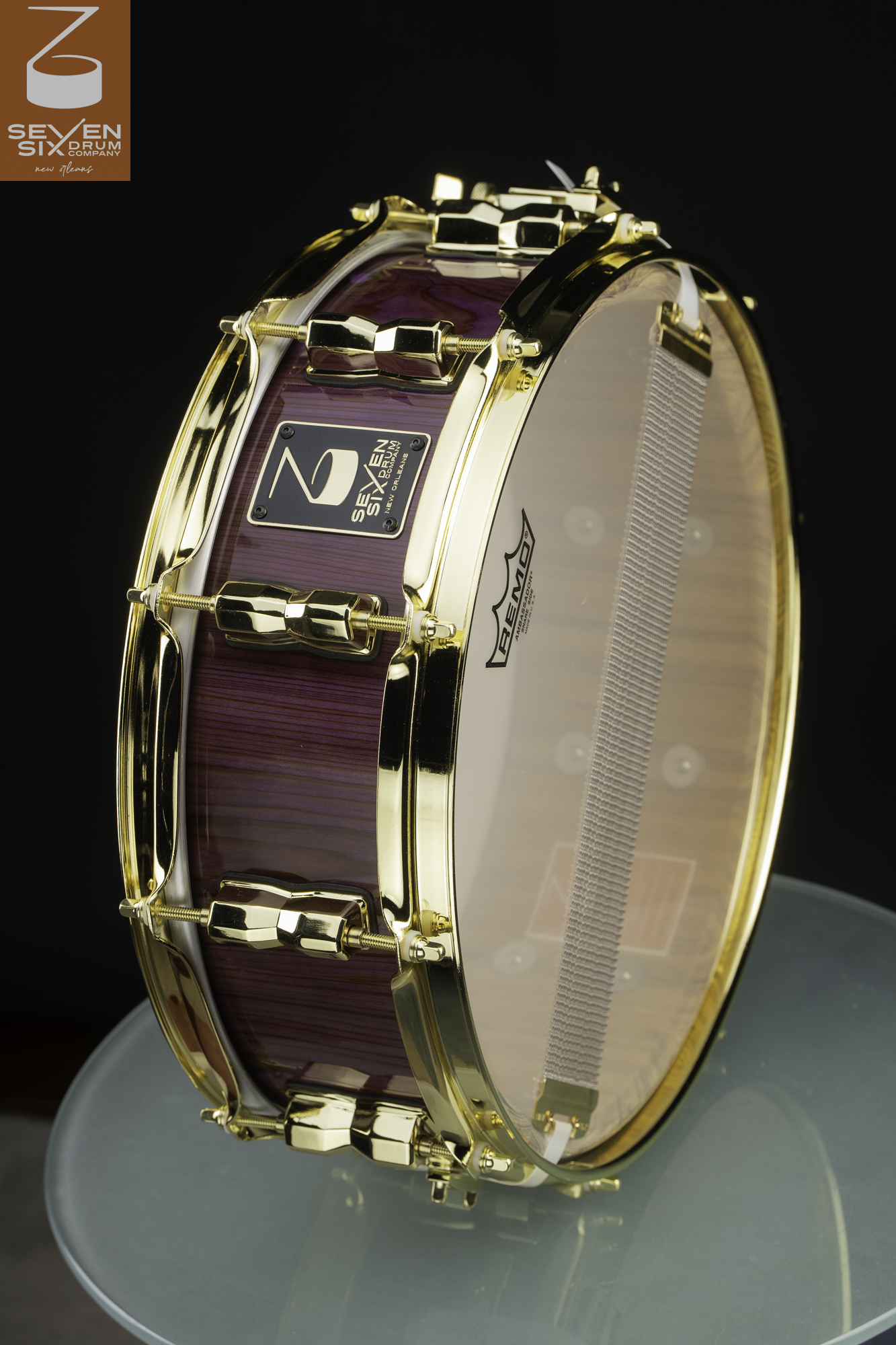 Handmade snare drum featuring a glossy purple wood shell and polished gold hardware.