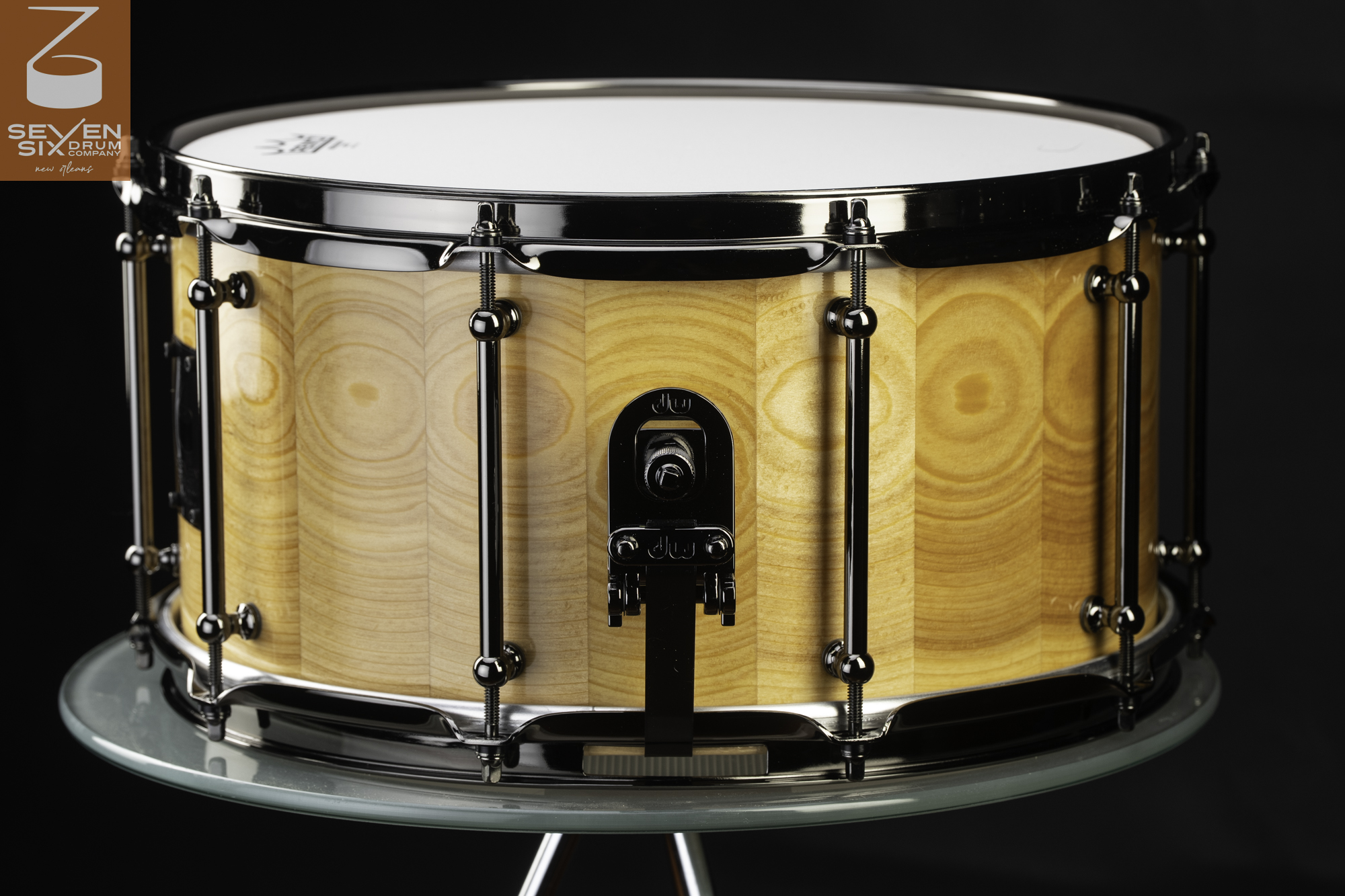 Handmade stave wood snare drum in a natural gloss finish, featuring black nickel tube lugs and a black throw-off.