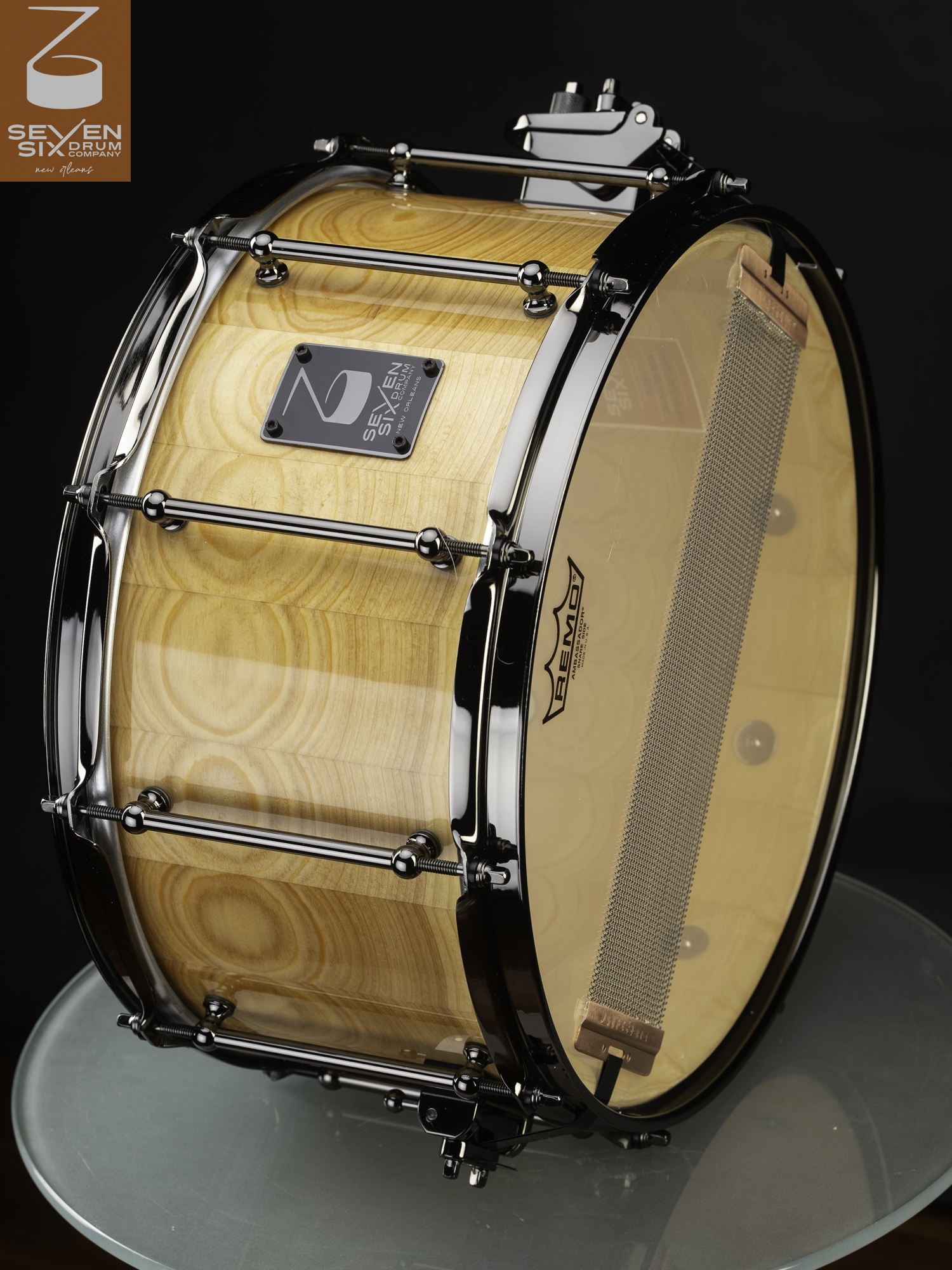 Segmented wood snare drum in a natural gloss finish with black nickel tube lugs and matching hoops.