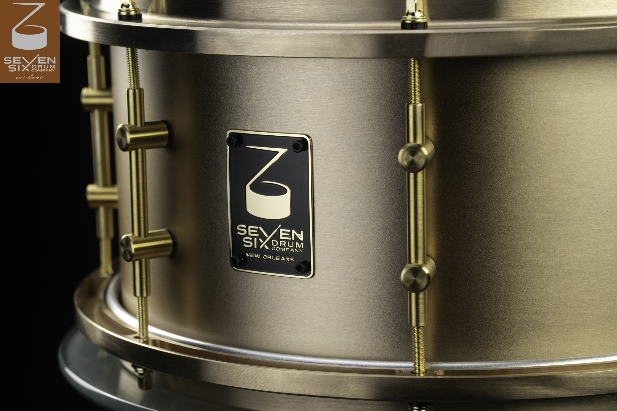 Handmade snare drum featuring a brushed bronze shell, matching metal hoops, and brass tube lugs.