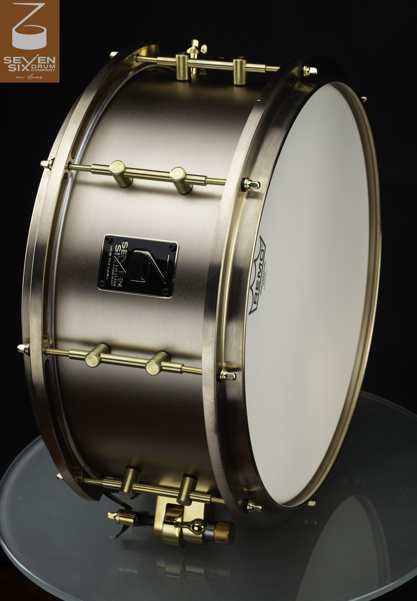 Handmade snare drum featuring a brushed bronze shell, matching bronze hoops, gold-toned minimalist lugs, and a coated head.
