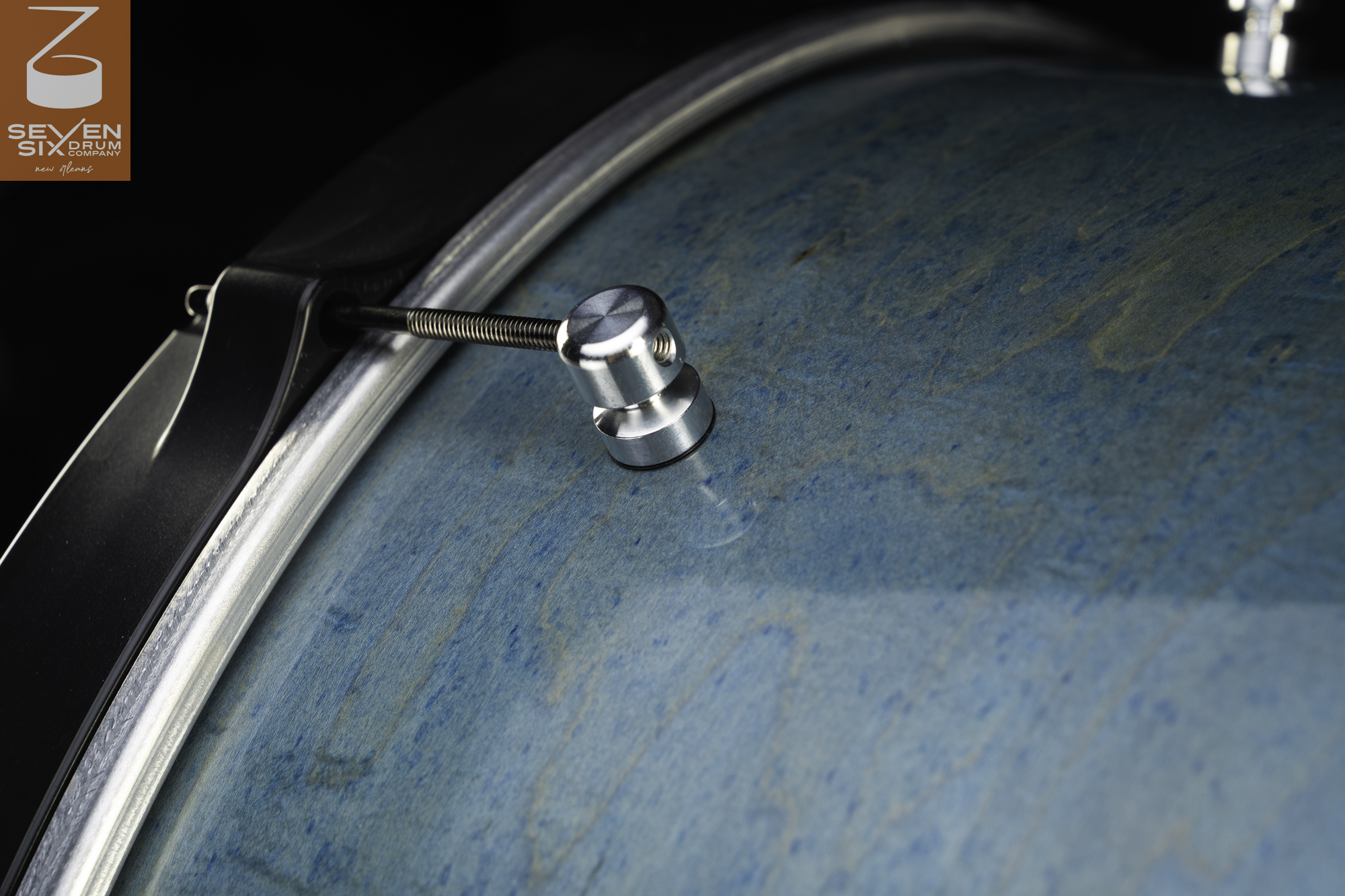 Handmade snare drum featuring a blue-stained wood shell, a machined silver single-point lug, and a black hoop.