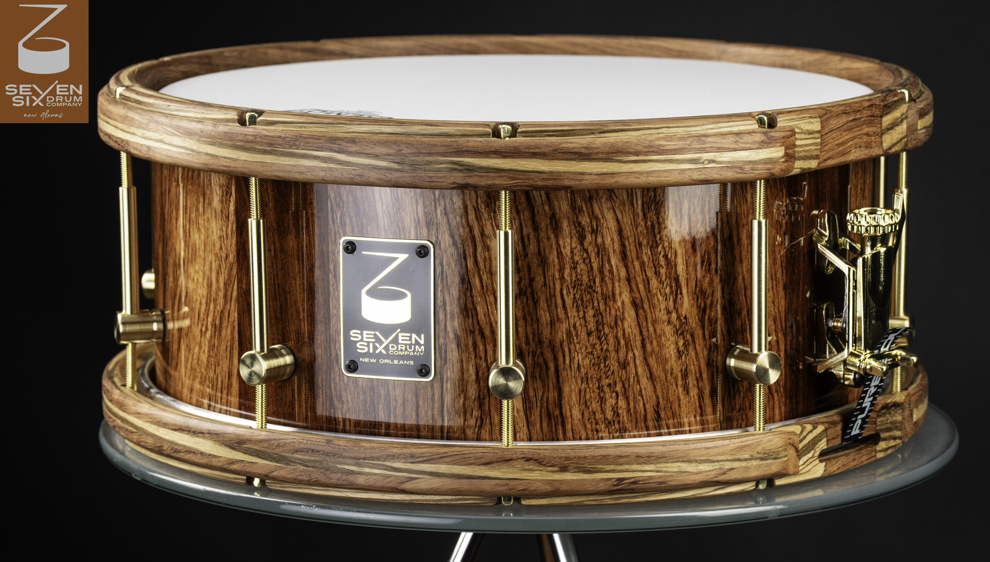 Handmade snare drum with a glossy natural wood shell, matching wooden hoops, and brushed brass tube lugs.