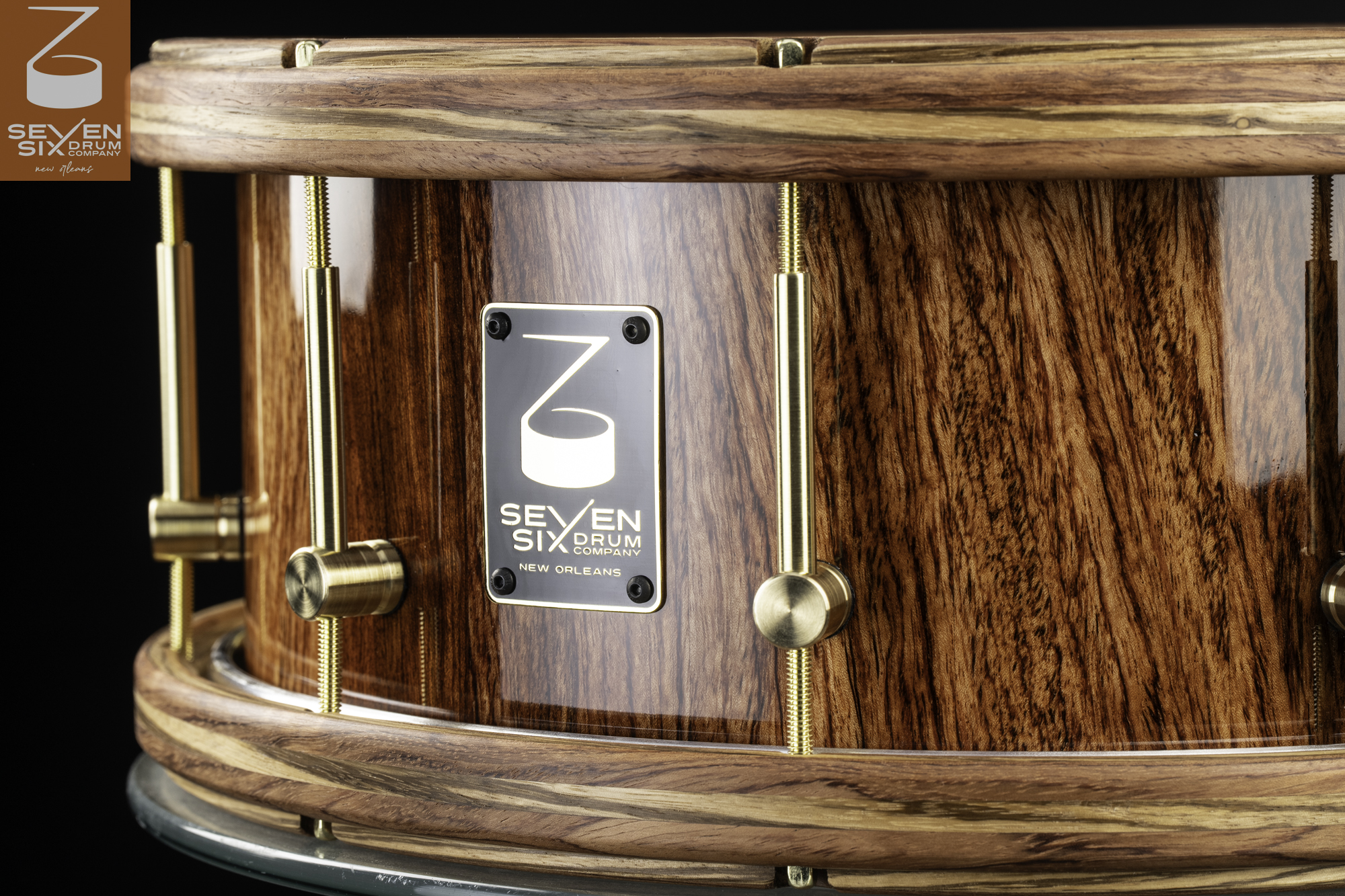 Handmade snare drum with a glossy natural wood shell, matching wooden hoops, and brushed brass tension hardware.