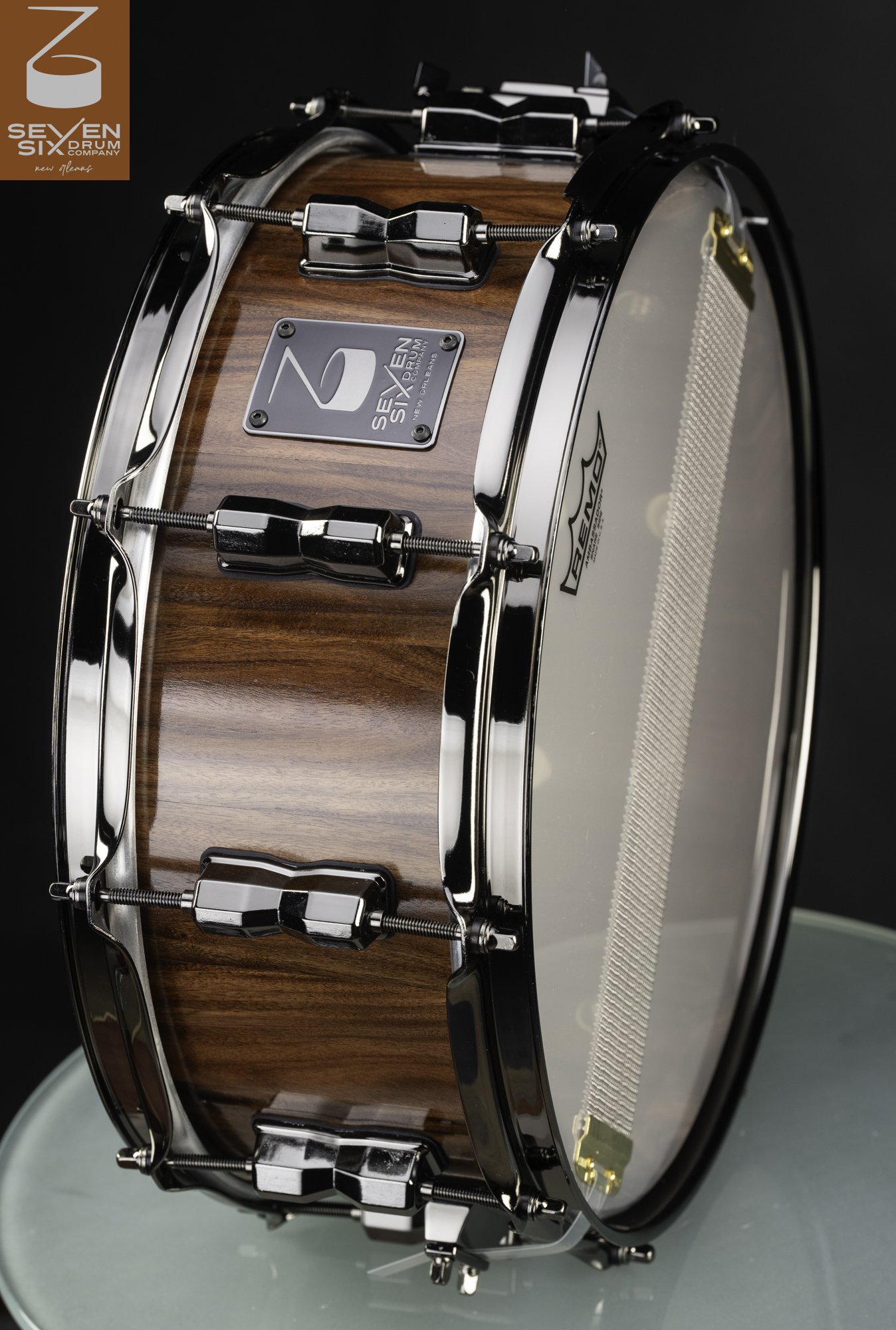 Handmade wood snare drum with a glossy brown finish, black nickel hoops, and faceted lugs.