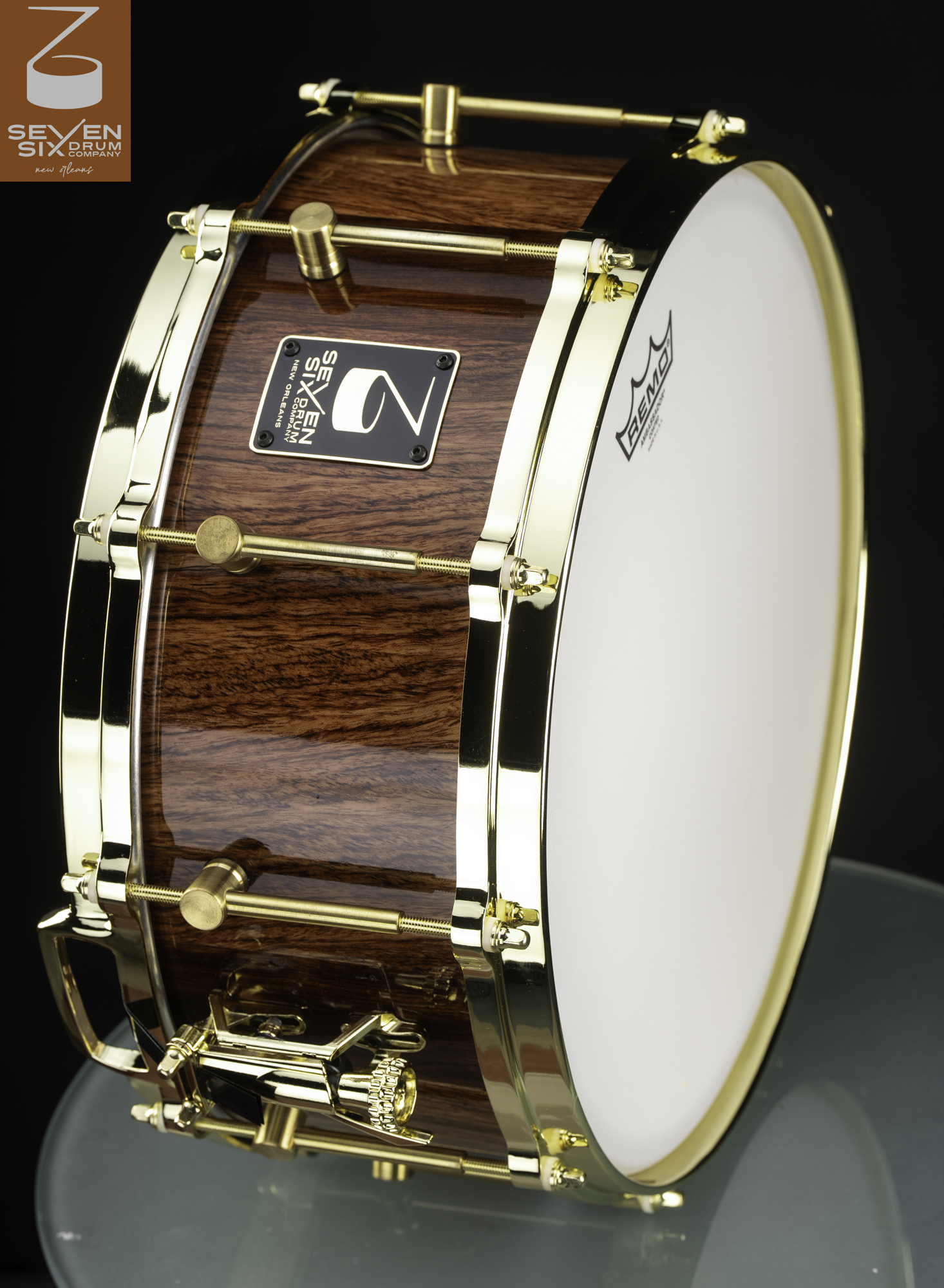 Handmade snare drum with a glossy natural wood shell, polished gold hoops, and matching hardware.