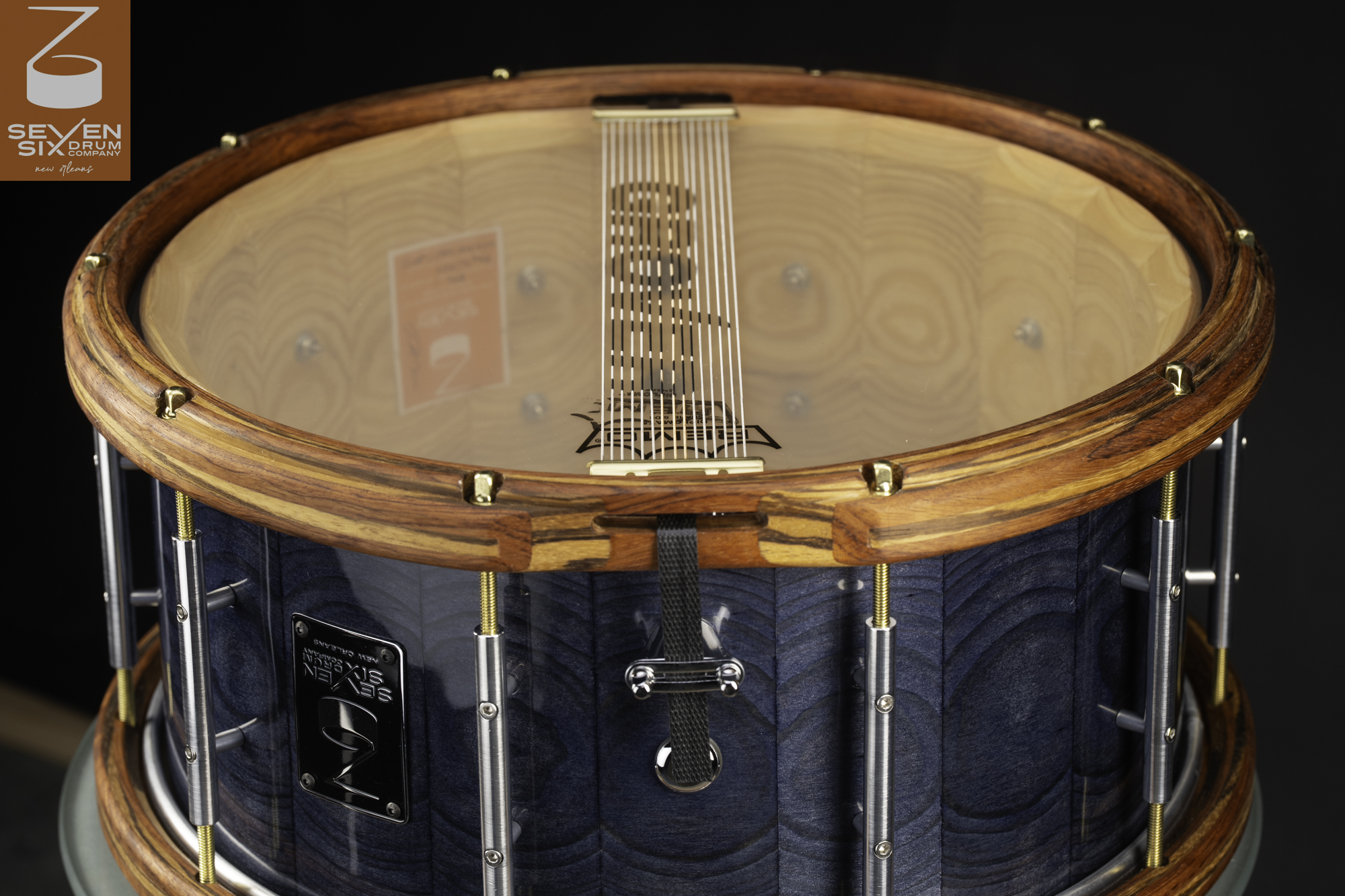 Handmade snare drum with a textured blue wood shell, natural wood hoops, and chrome tube lugs with brass tension rods.
