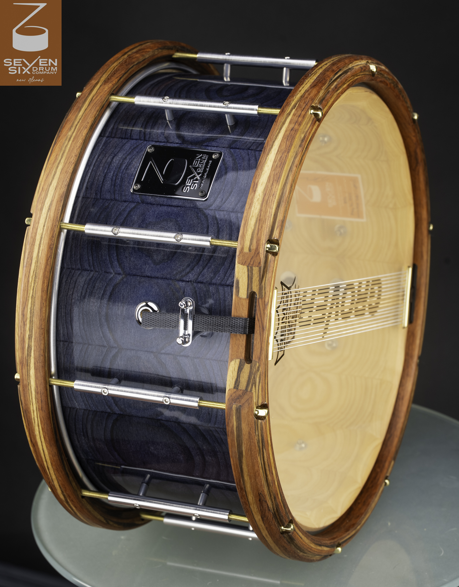 Handmade snare drum with a gloss blue stained wood shell, striped natural wood hoops, and chrome and brass tube lugs.