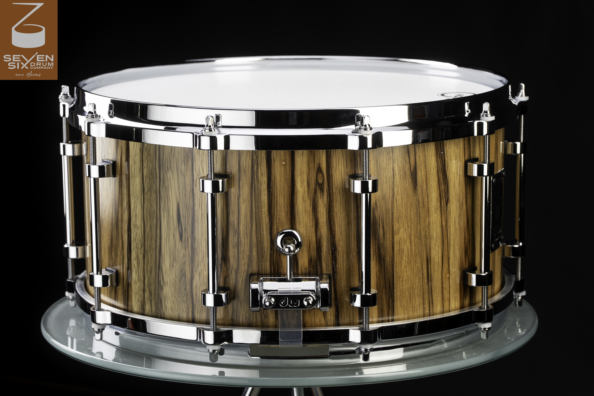 Handmade snare drum with a glossy, striped natural wood shell, polished chrome hardware, and a DW throw-off.
