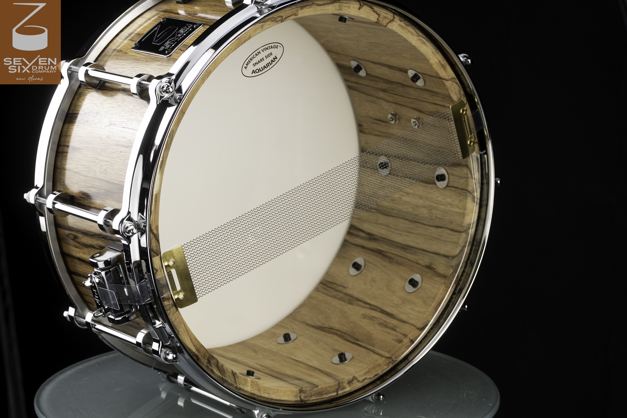 Handmade snare drum with a glossy natural wood shell, chrome tube lugs, and brass-ended wire snares.