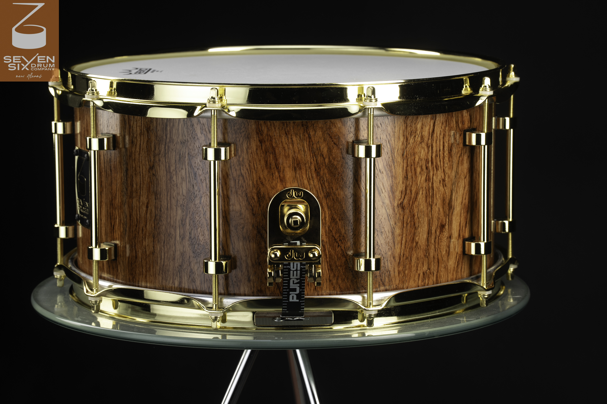 Handmade wood snare drum with a natural vertical grain finish, polished gold hoops, tube lugs, and throw-off.