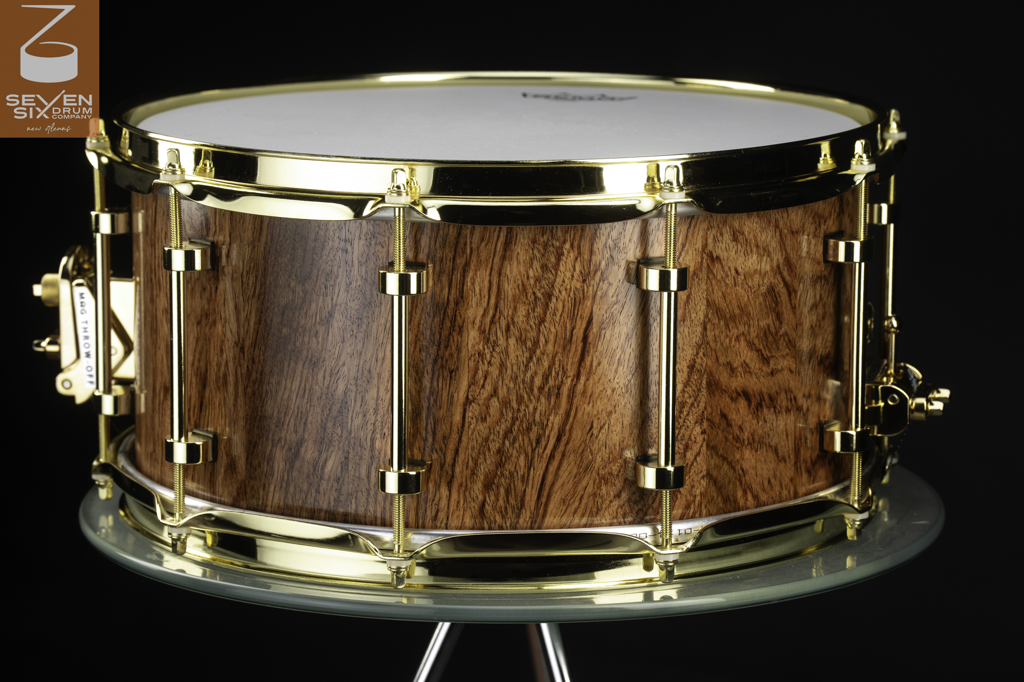 Handcrafted natural wood snare drum with a gloss finish, polished gold hoops, tube lugs, and a MAG throw-off.