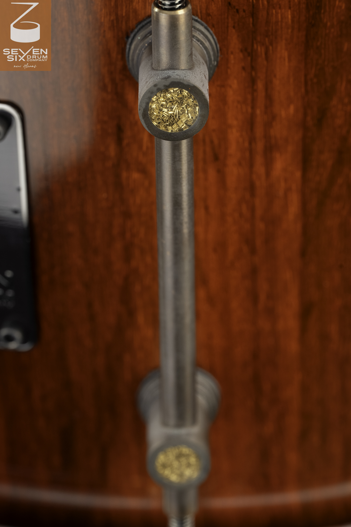 Gloss reddish wood snare drum shell featuring a brushed metal tube lug with brass shaving inlays.