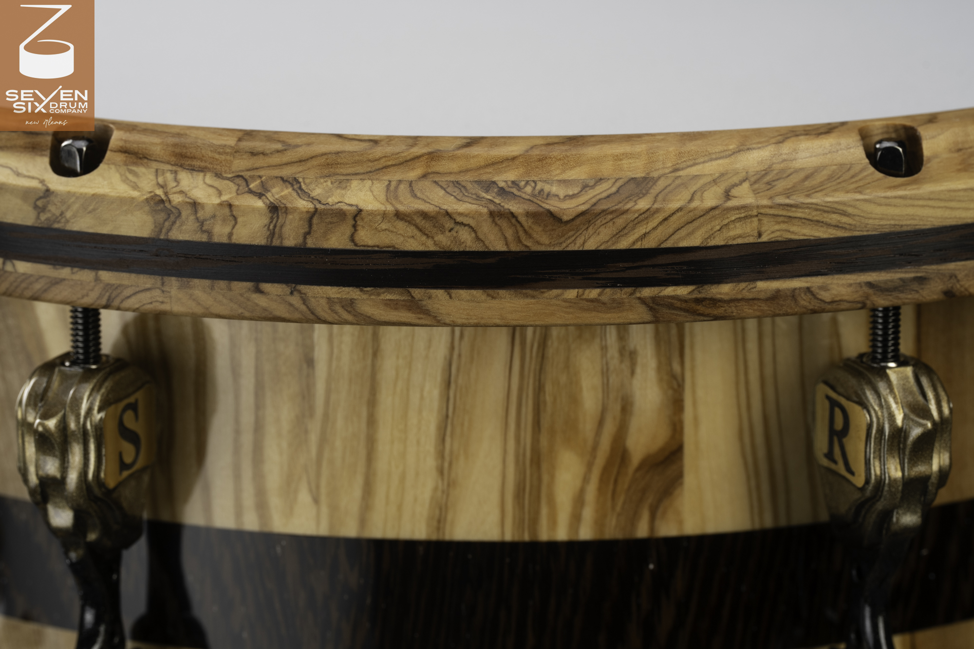 Handmade snare drum with a glossy figured wood shell, matching segmented wooden hoop, and custom antique bronze lugs.