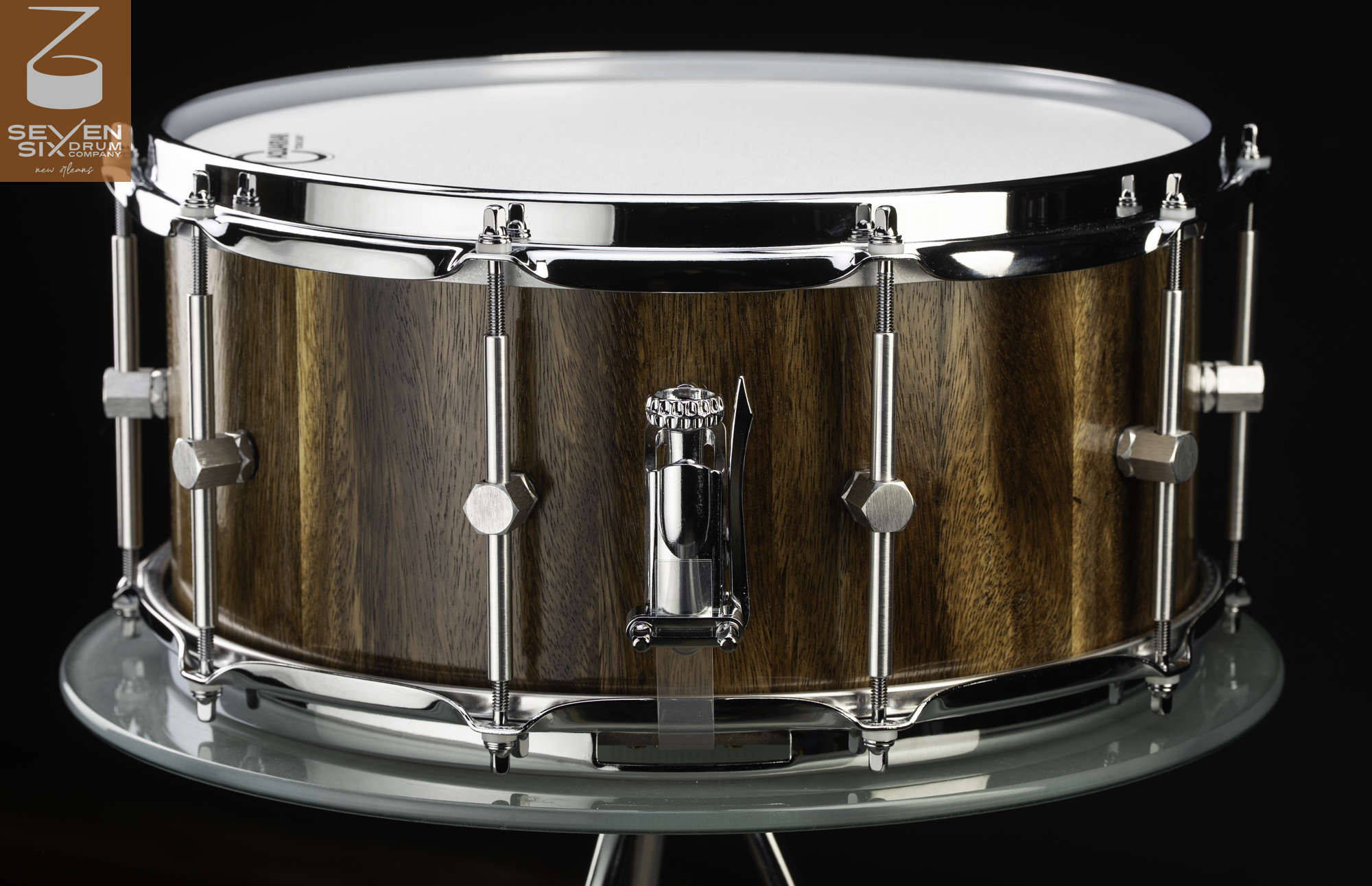 Handmade snare drum in glossy natural walnut featuring chrome hoops, tubular hex lugs, and a snare throw-off.