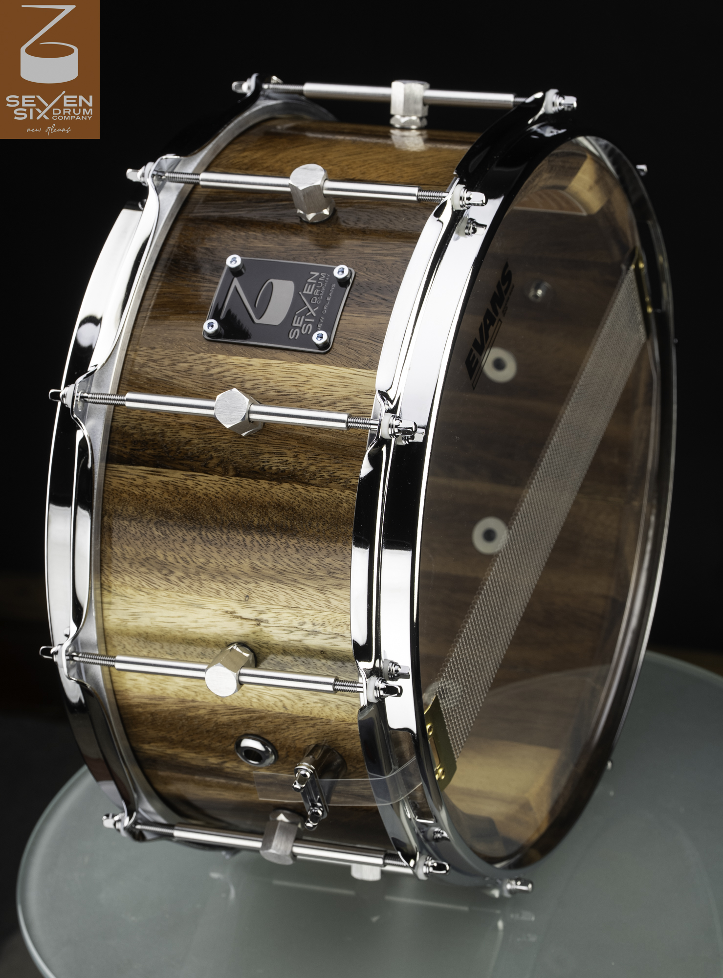 Glossy natural wood snare drum with chrome triple-flange hoops, center-mount lugs, and a clear Evans resonant head.