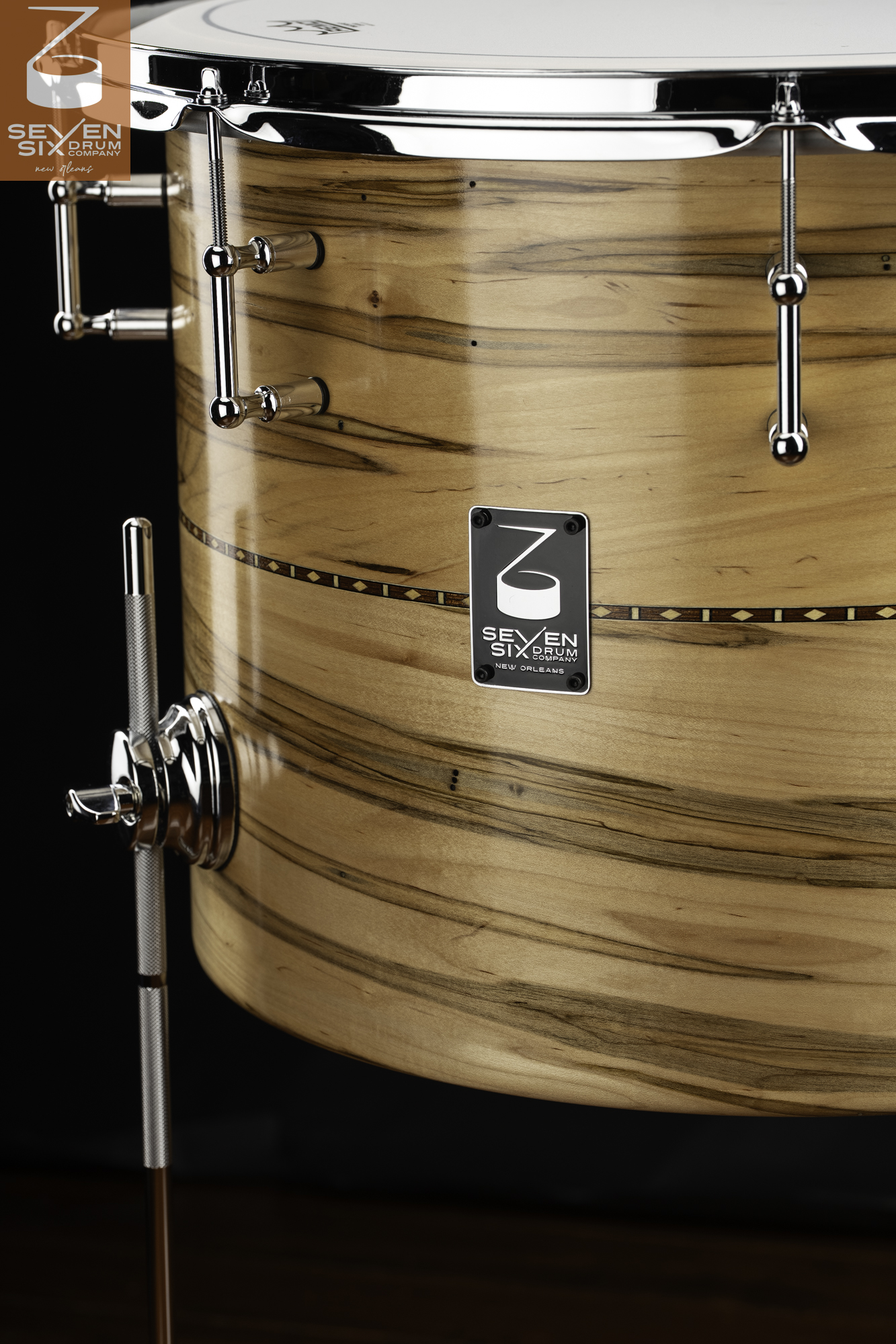 Gloss-finished natural wood drum featuring an inlaid wood band, chrome tube lugs, and a chrome leg bracket.