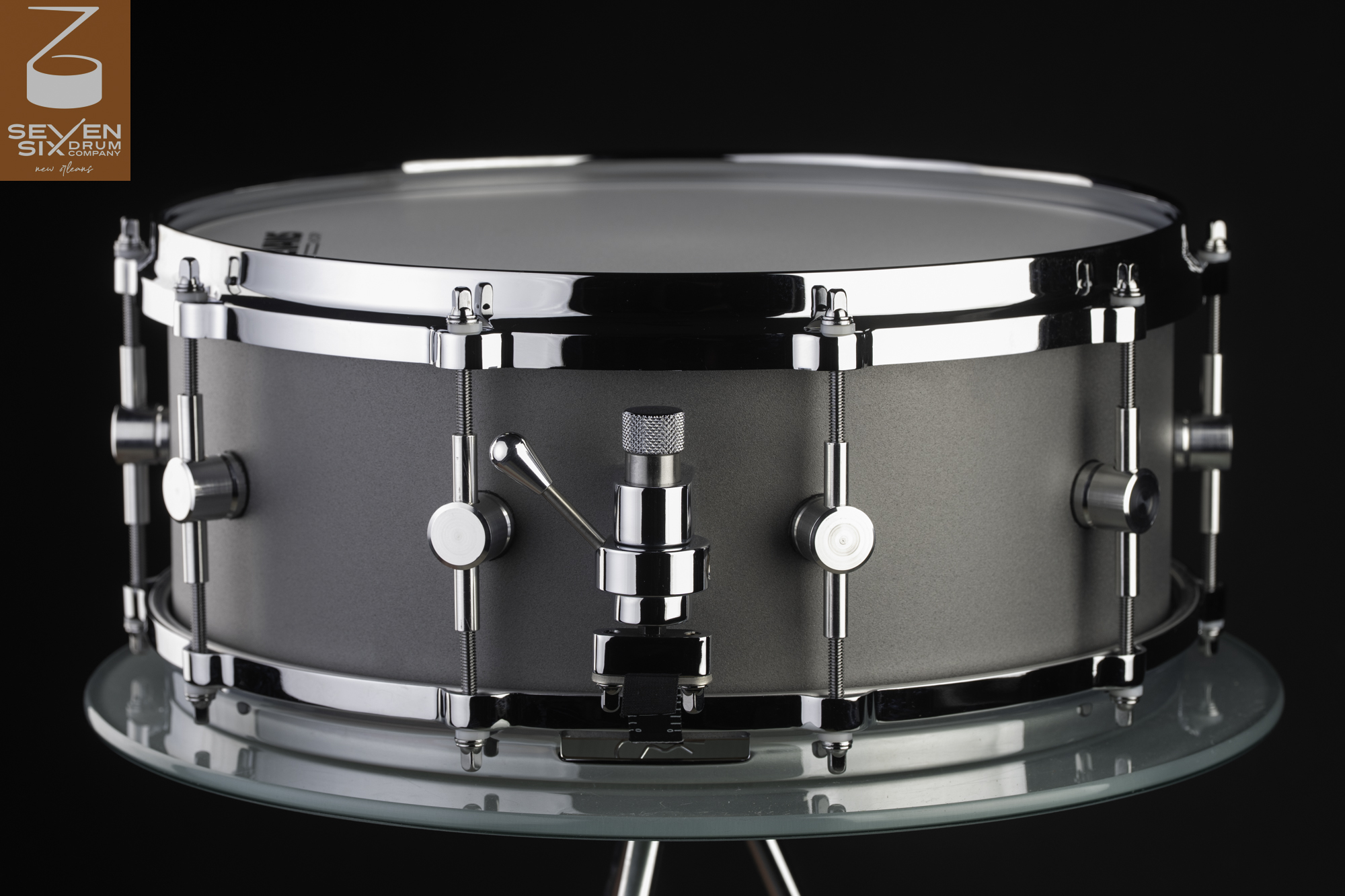Matte gray metal snare drum featuring polished chrome hoops, round center-mounted lugs, and a chrome lever throw-off.