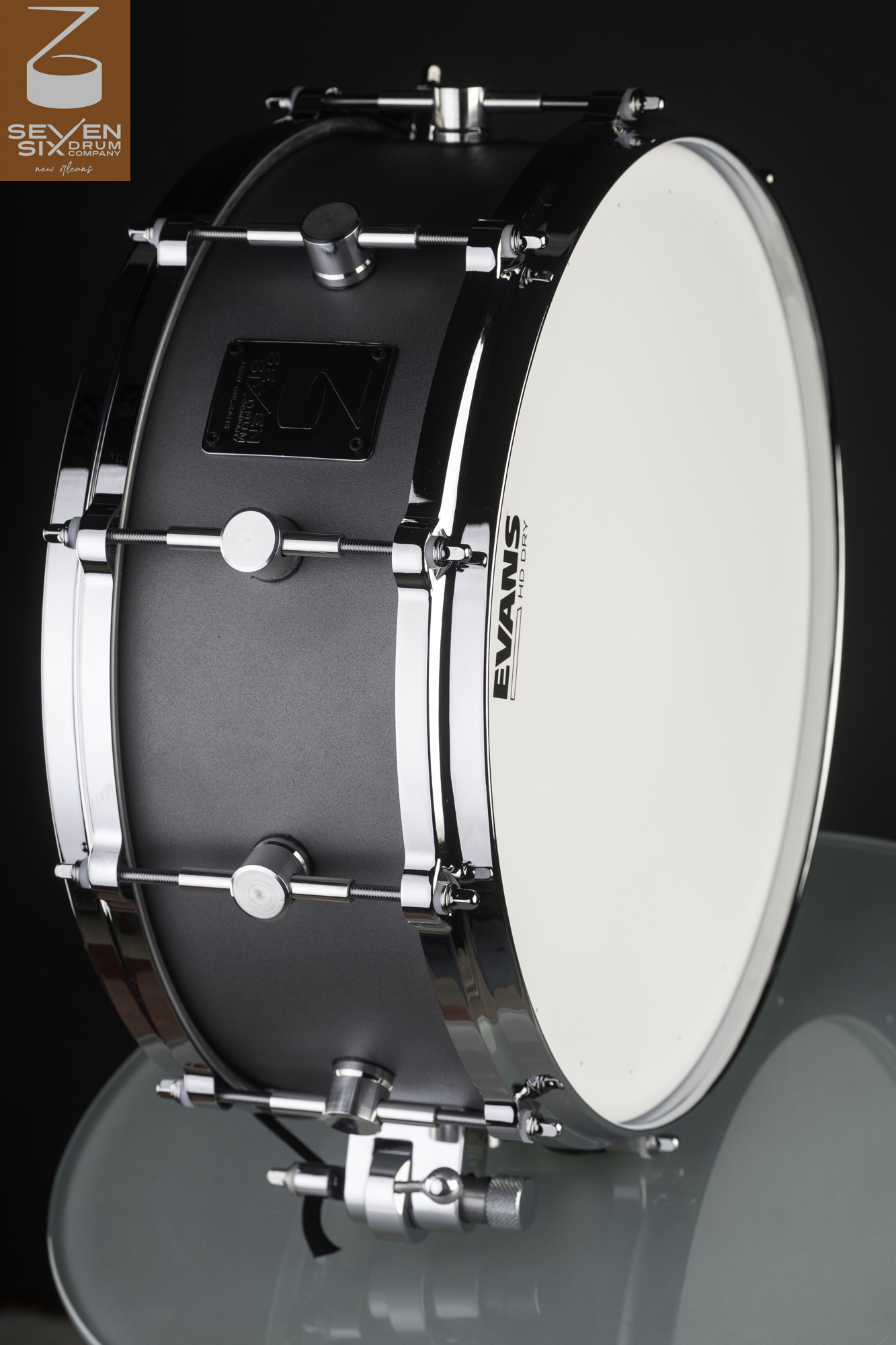 Handmade snare drum with a matte dark gray shell, polished chrome hoops, round single-point lugs, and a white drumhead.