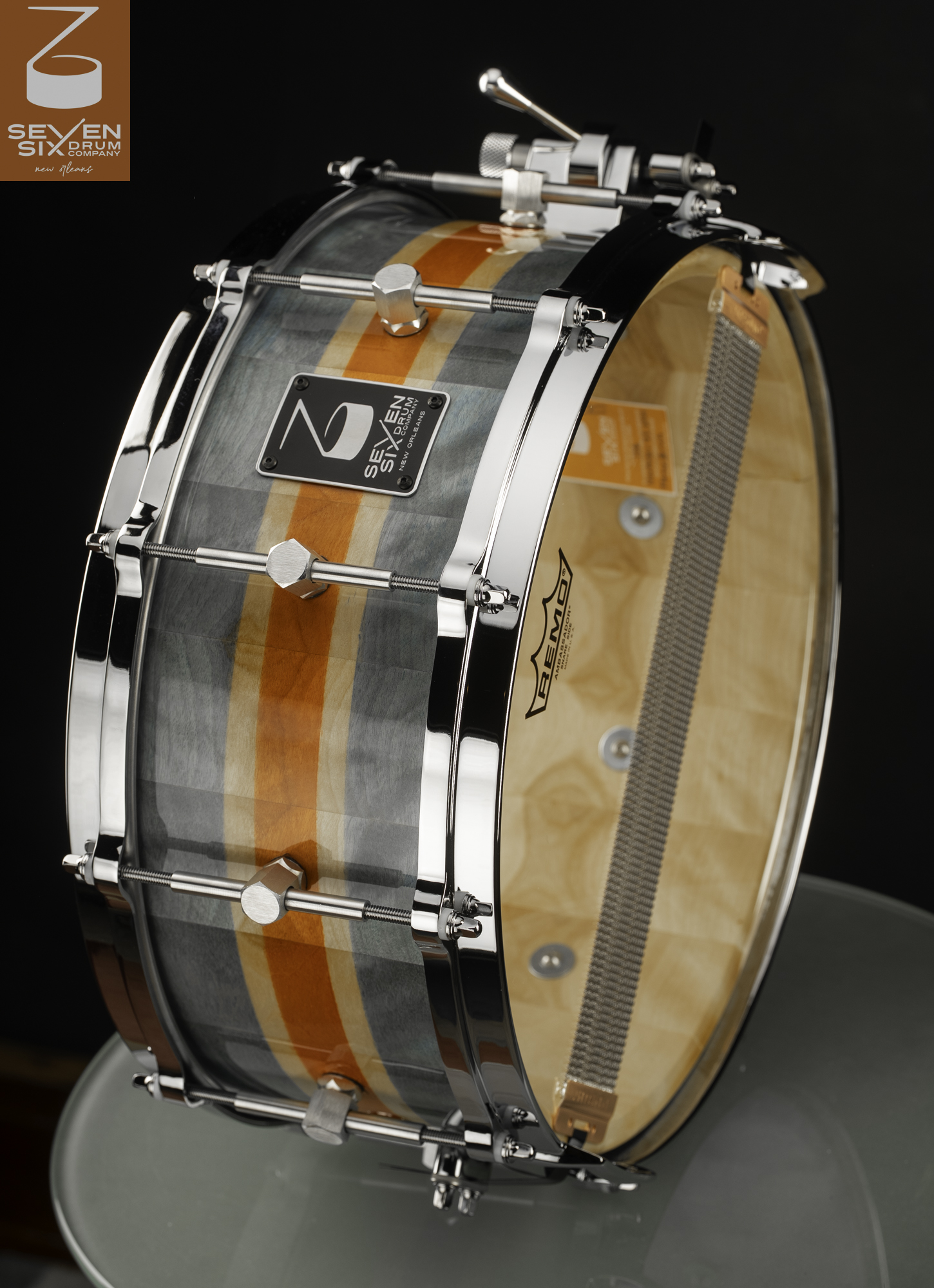 Handmade wood snare drum with a grey and orange striped finish, polished chrome hoops, and center lugs.
