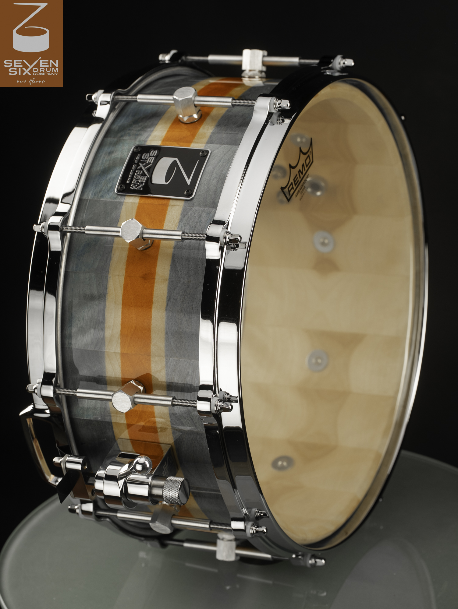 Handmade wood snare drum with a glossy blue-gray and orange striped finish, chrome hoops, and a polished throw-off.