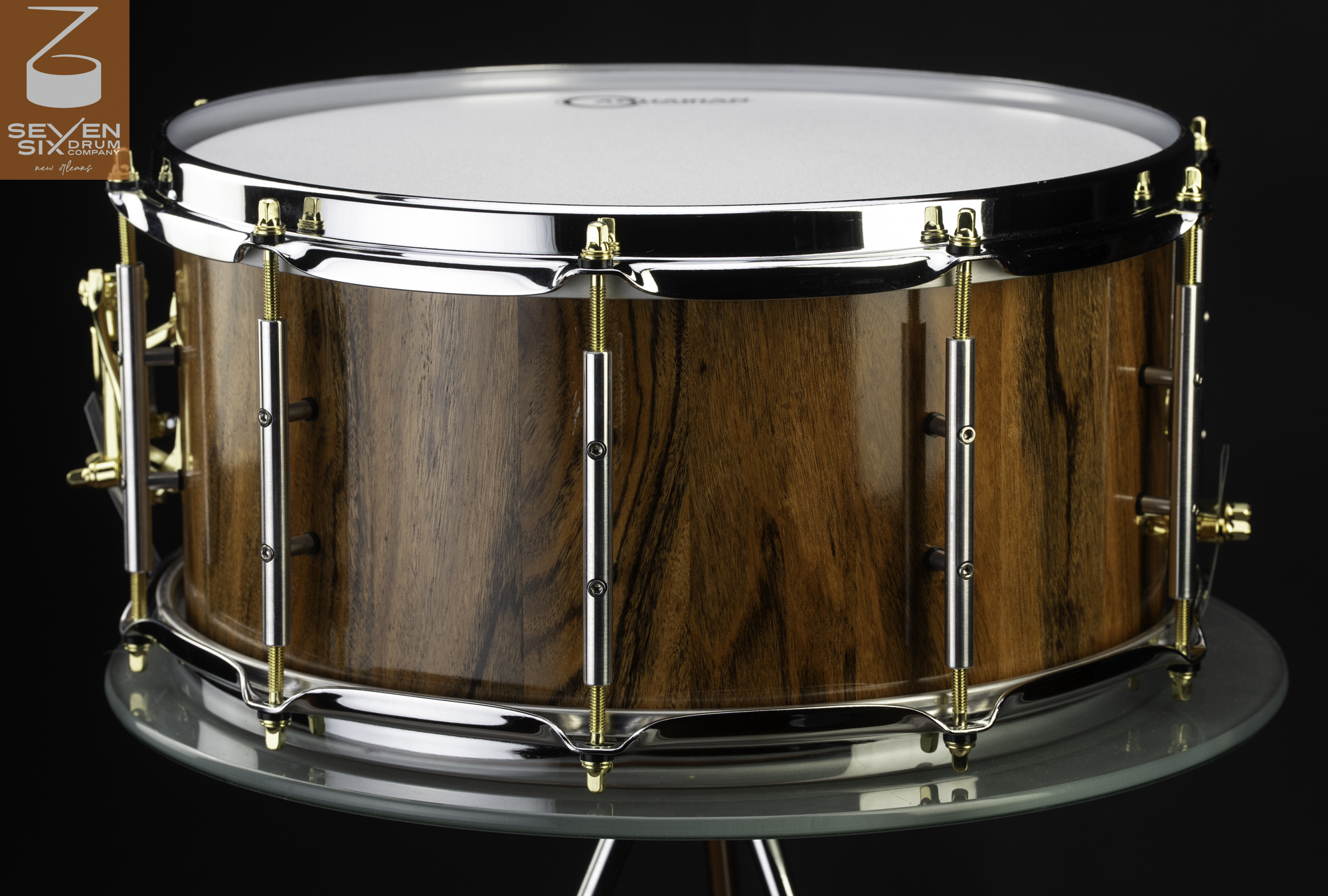 Handmade snare drum with a glossy natural wood finish, chrome hoops, and silver tube lugs with gold tension rods.