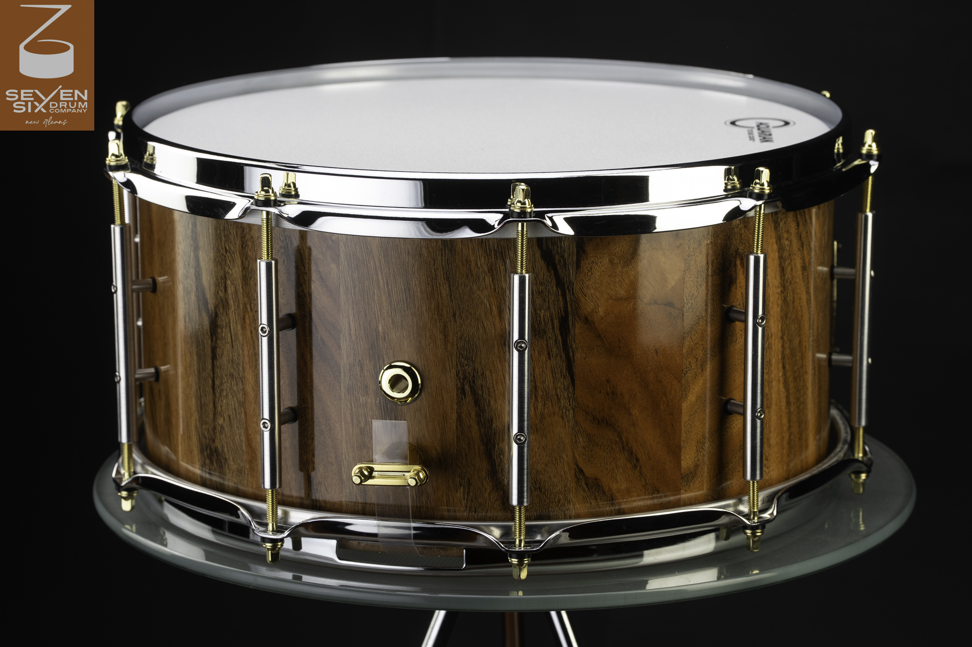 Handmade snare drum with a high-gloss natural wood shell, chrome hoops, silver tube lugs, and gold tension rods.