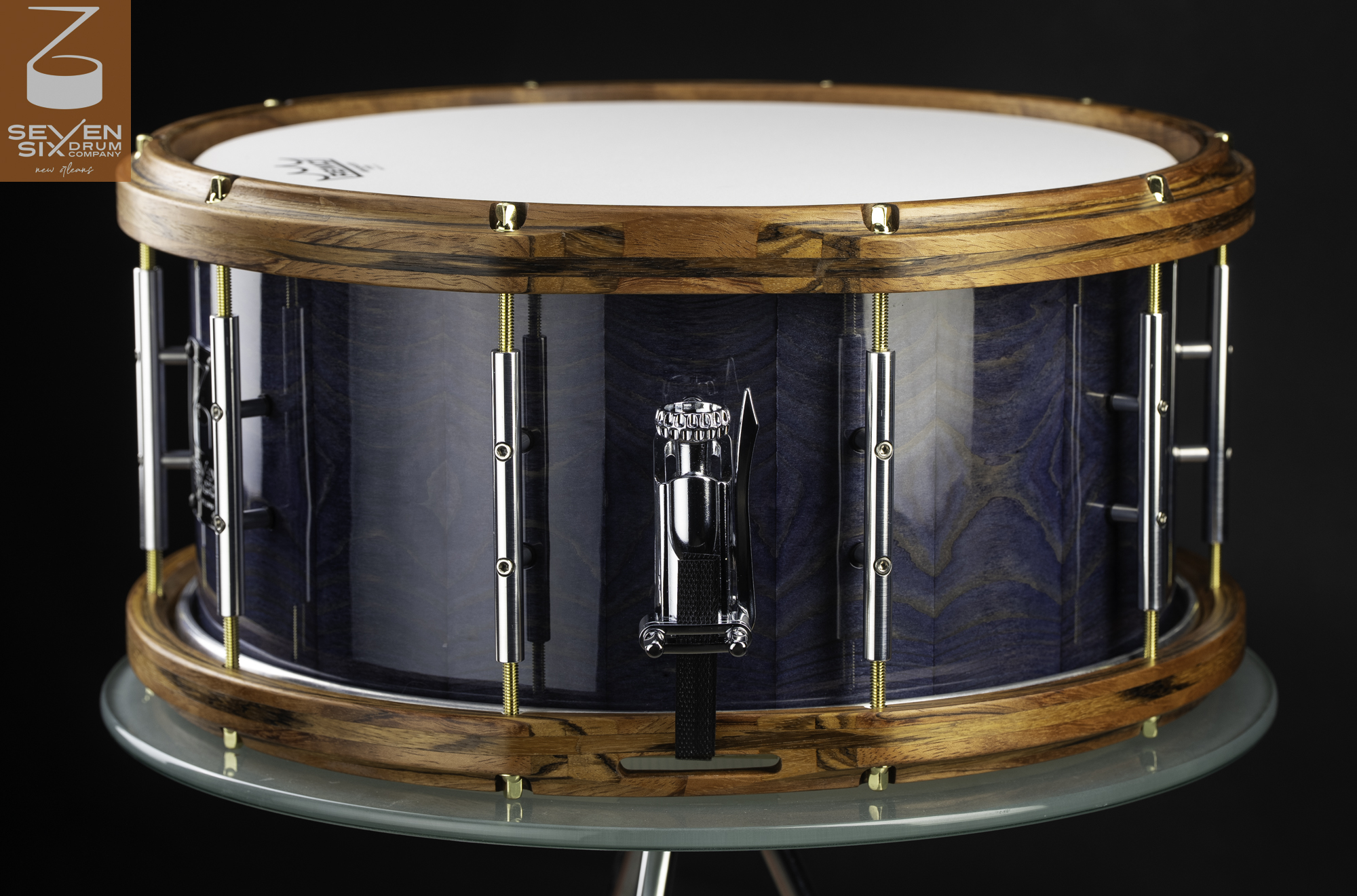 Handmade snare drum featuring a glossy blue wood shell, natural wood hoops, and polished chrome tube lugs and throw-off.