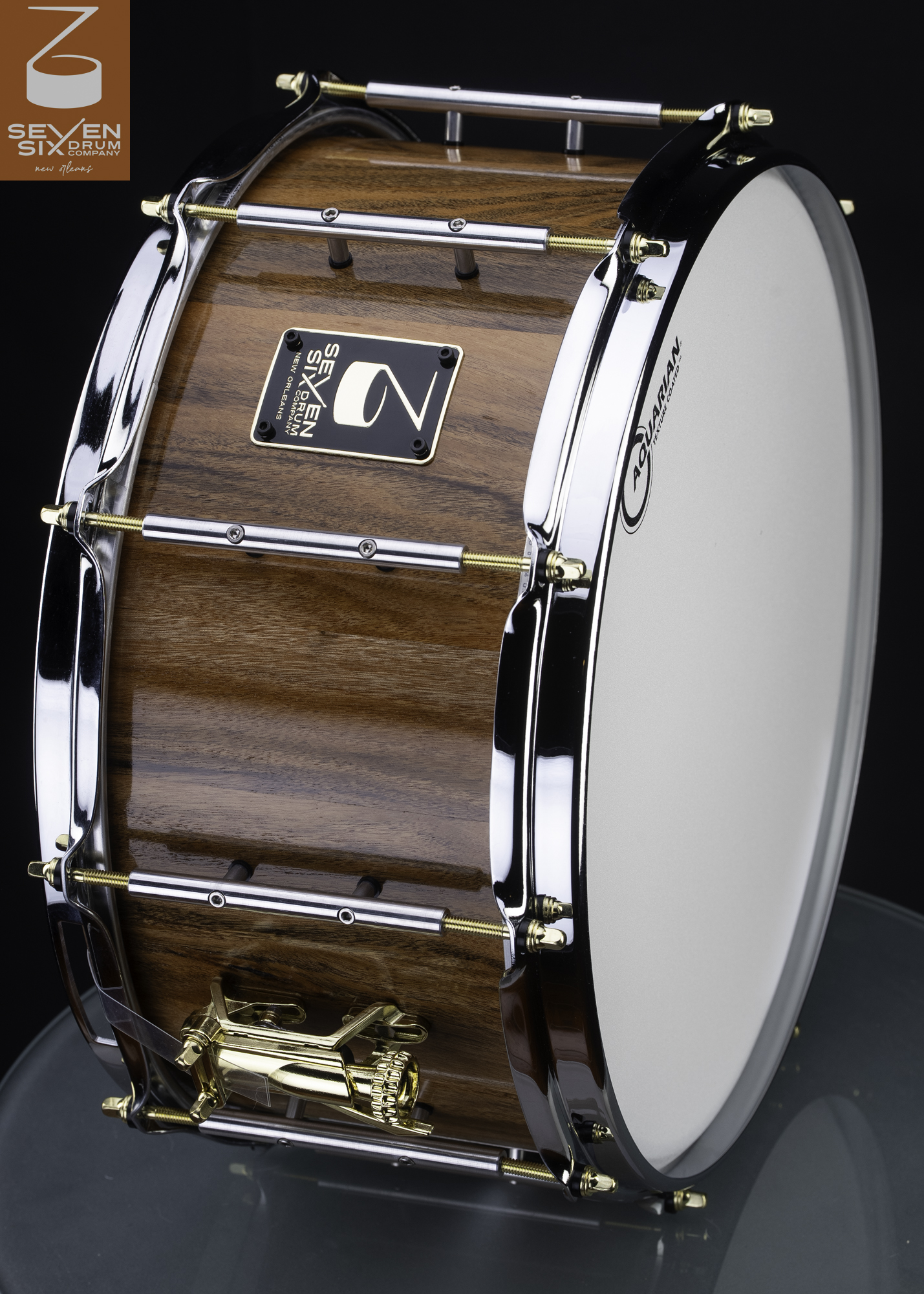 Natural wood snare drum with a high-gloss finish, chrome tube lugs, and gold tension rods and throw-off.
