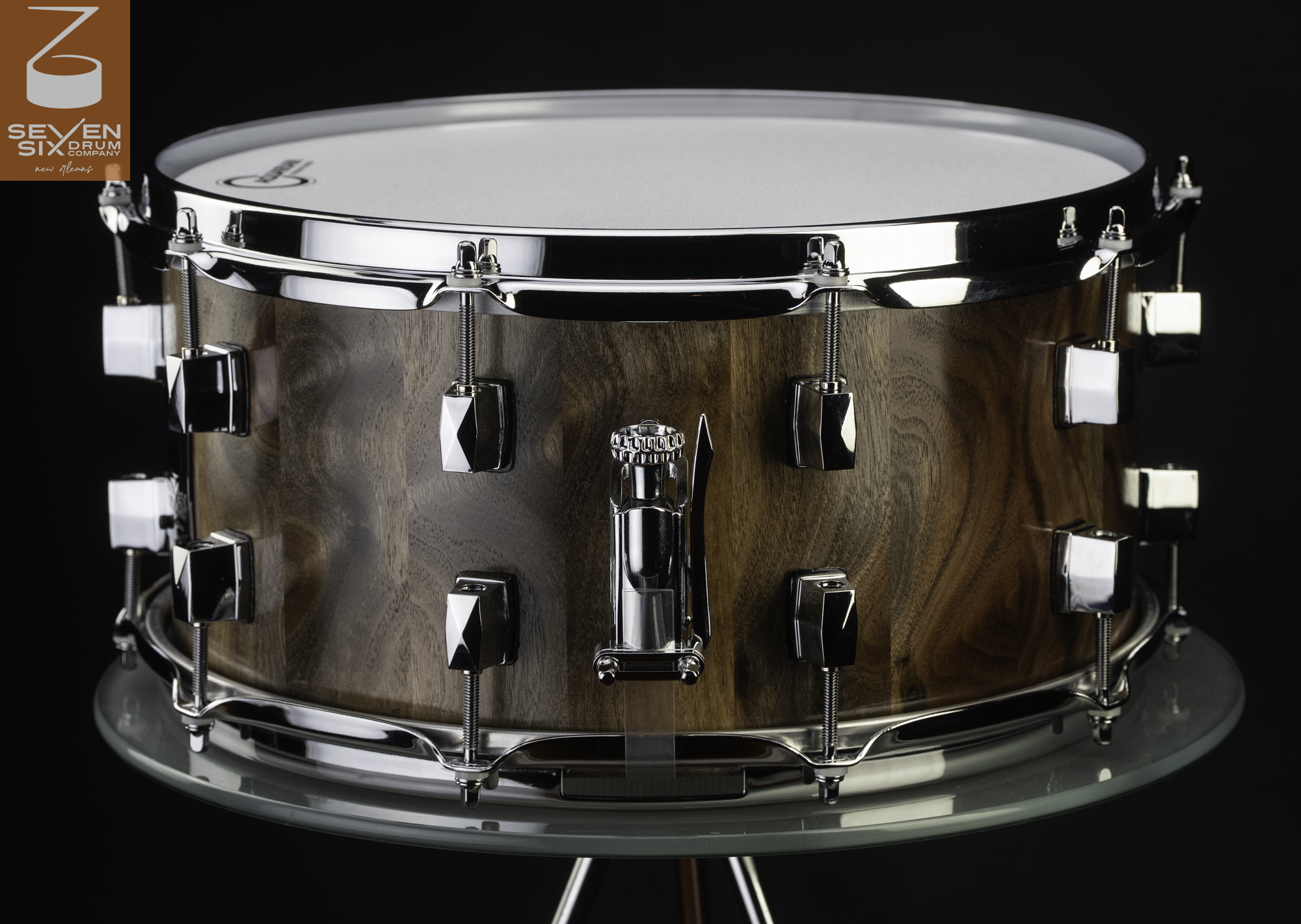 Handmade walnut snare drum featuring a natural wood grain finish, chrome hoops, faceted lugs, and a snare throw-off.